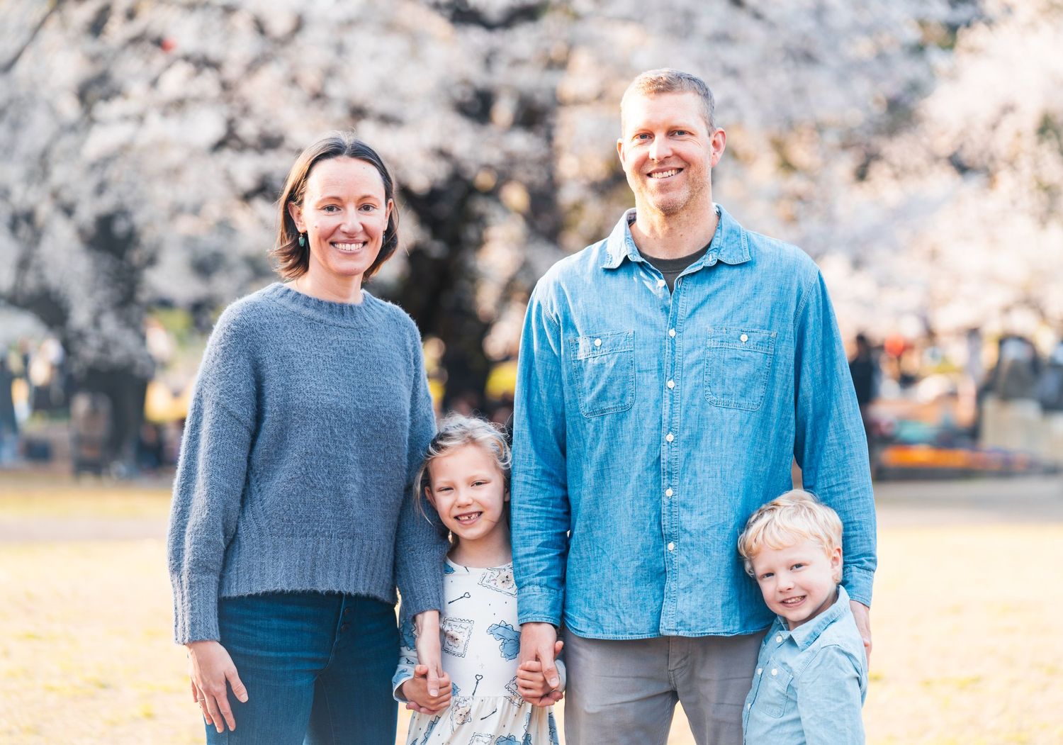Cheerful family gathered together under flowering cherry trees.
