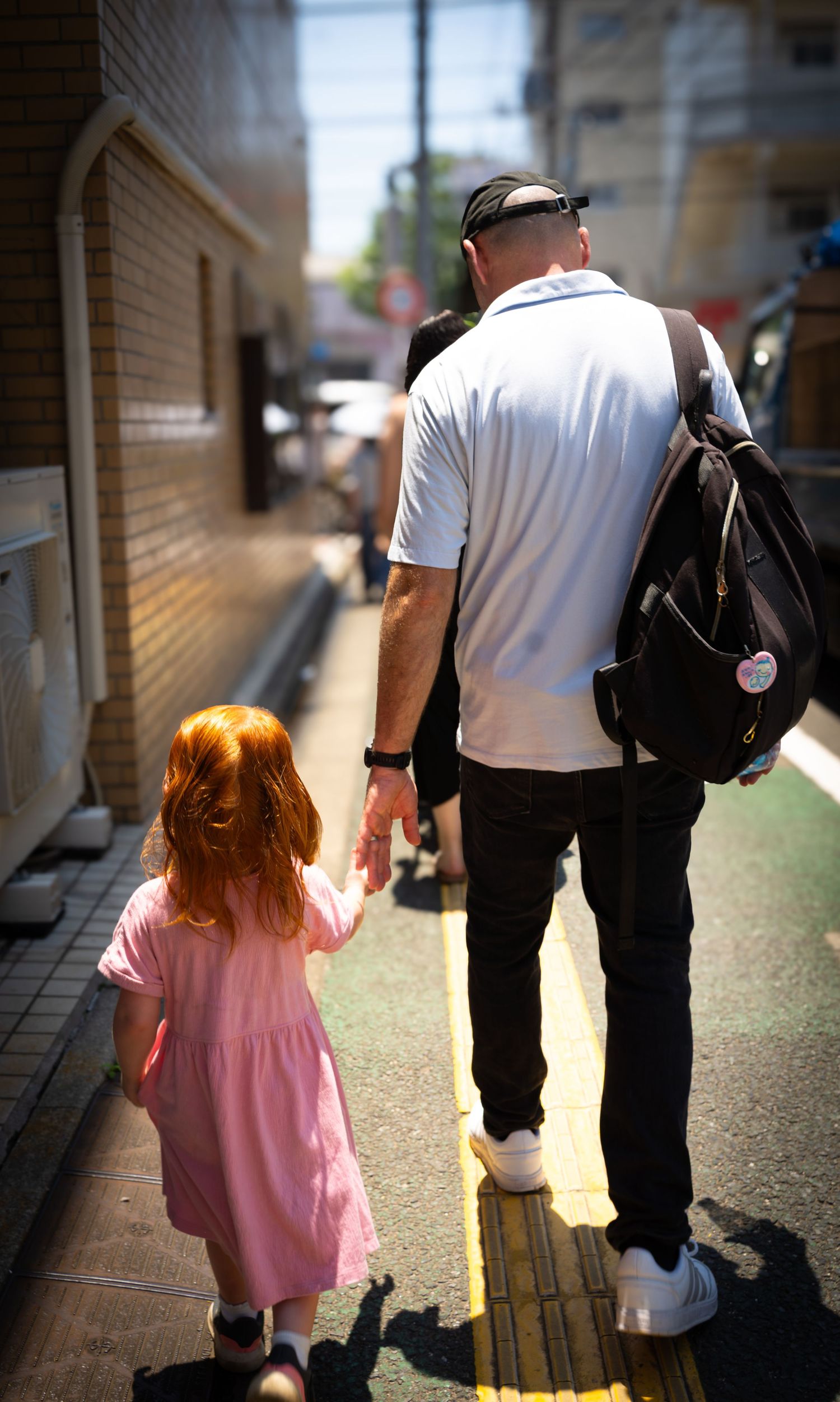 A series of images showing a person in a white shirt and black backpack walking with a child in pink along a corridor.