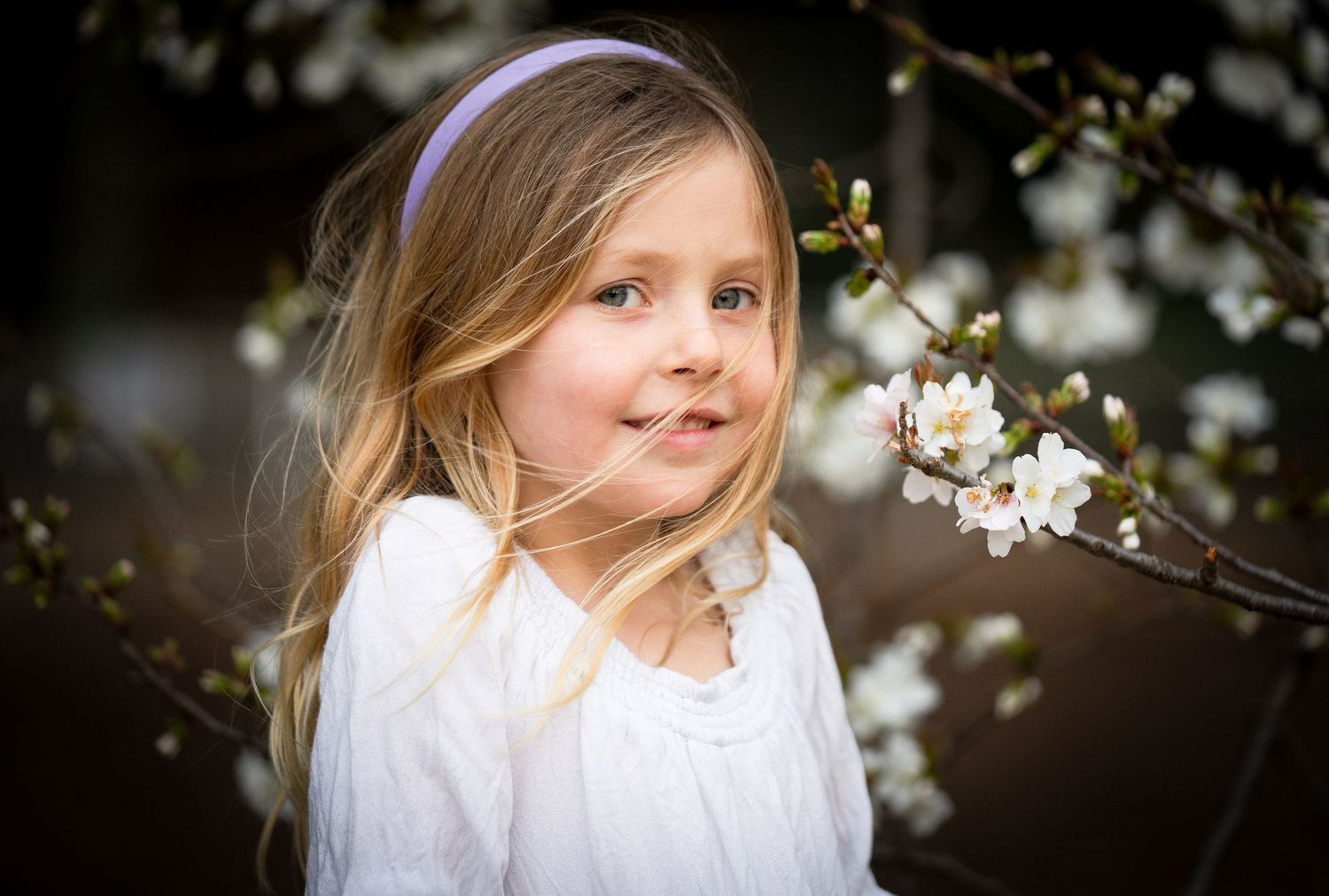 A dreamy spring portrait with white blossoms and a soft natural background.