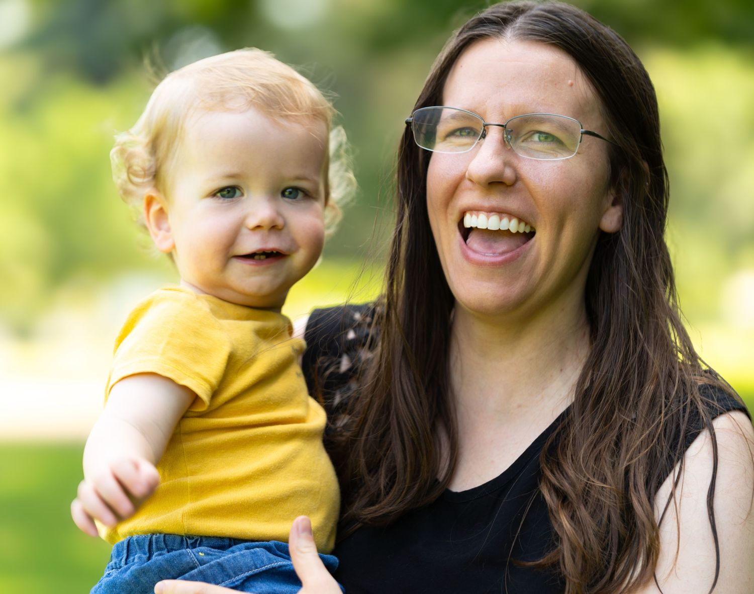 Happy family enjoying playful moments together outdoors in bright yellow and blue clothing.