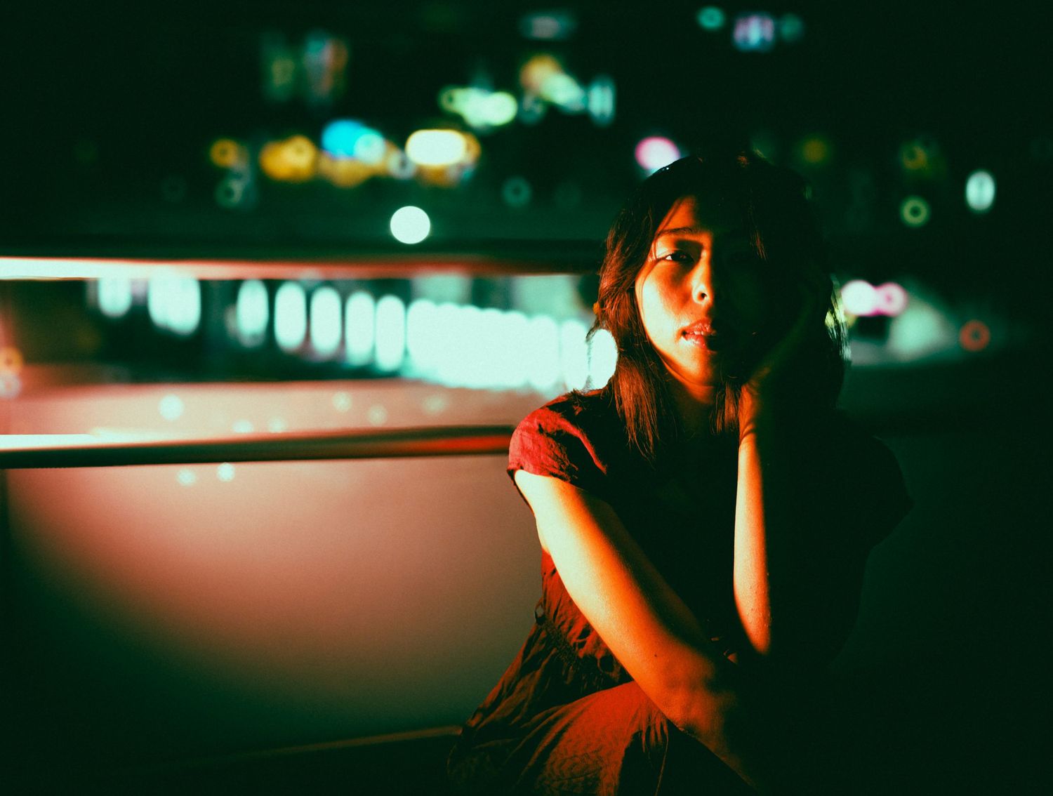 Moody nighttime portrait with city lights bokeh in background.