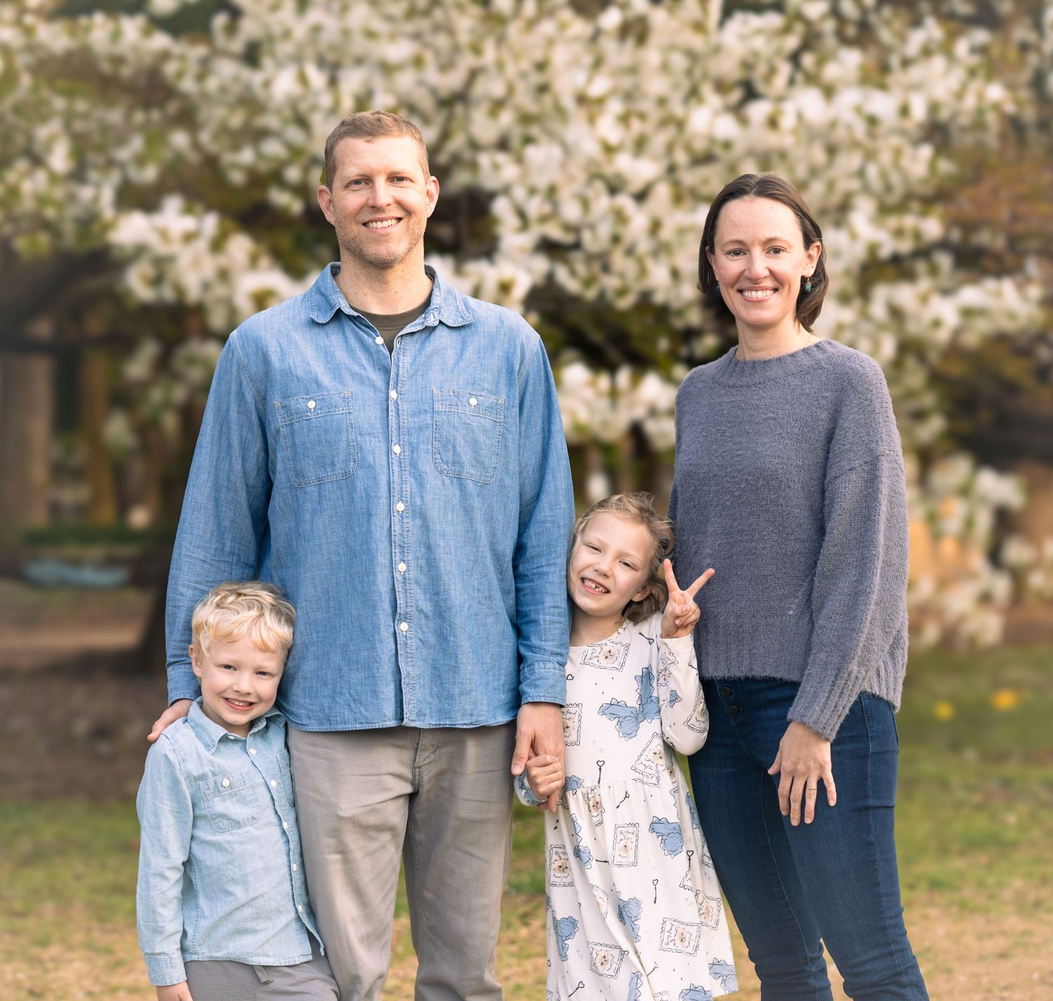 Family portrait under blooming cherry blossoms in springtime.
