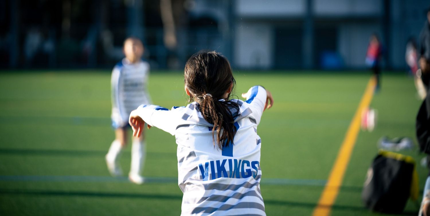 Athletic player in white Vikings jersey practicing on sports field.