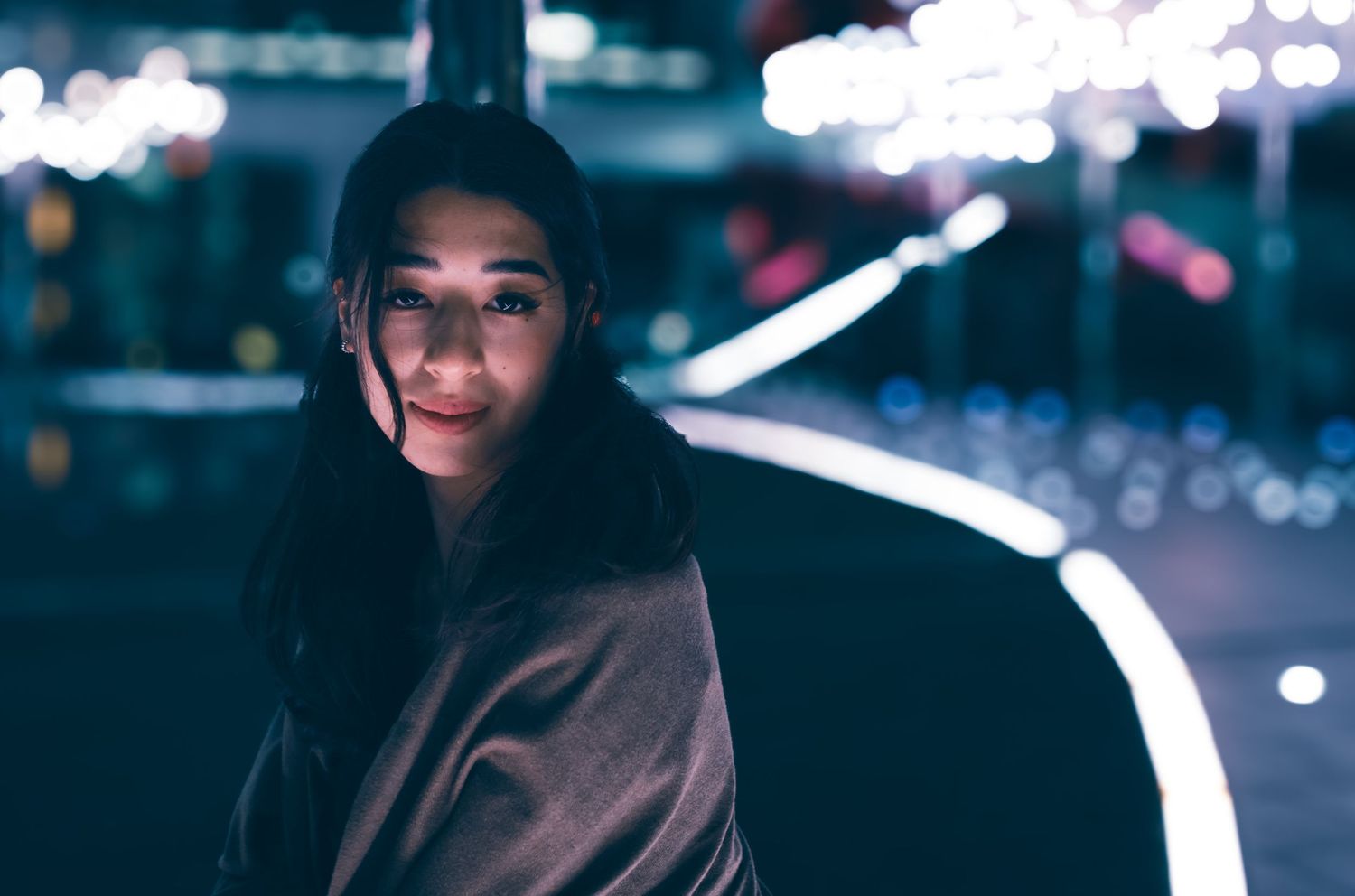 Nighttime urban portrait with bokeh lights and dark atmospheric mood.