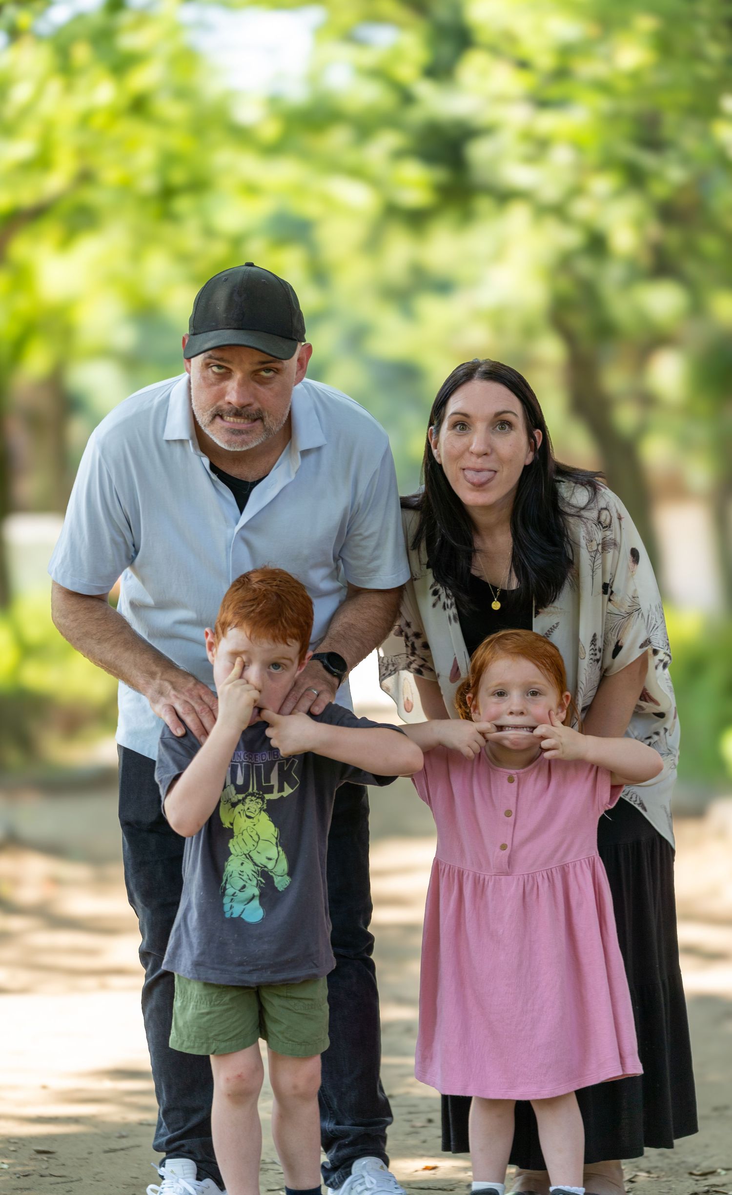 A family with a toddler poses for candid photos in a sunlit forest path, creating a sequence of playful moments.