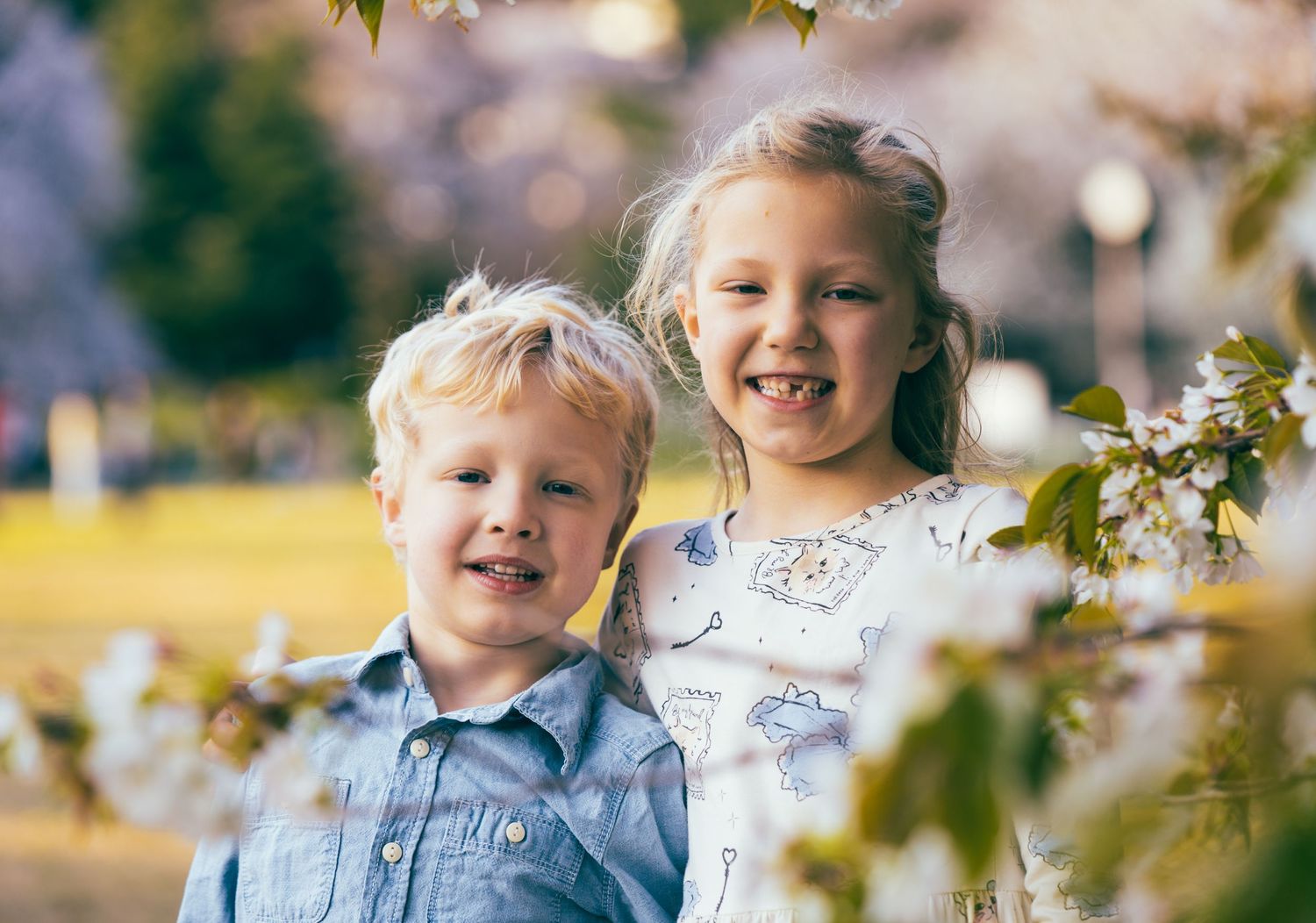 Two children sharing a joyful moment together in a sunny garden setting.