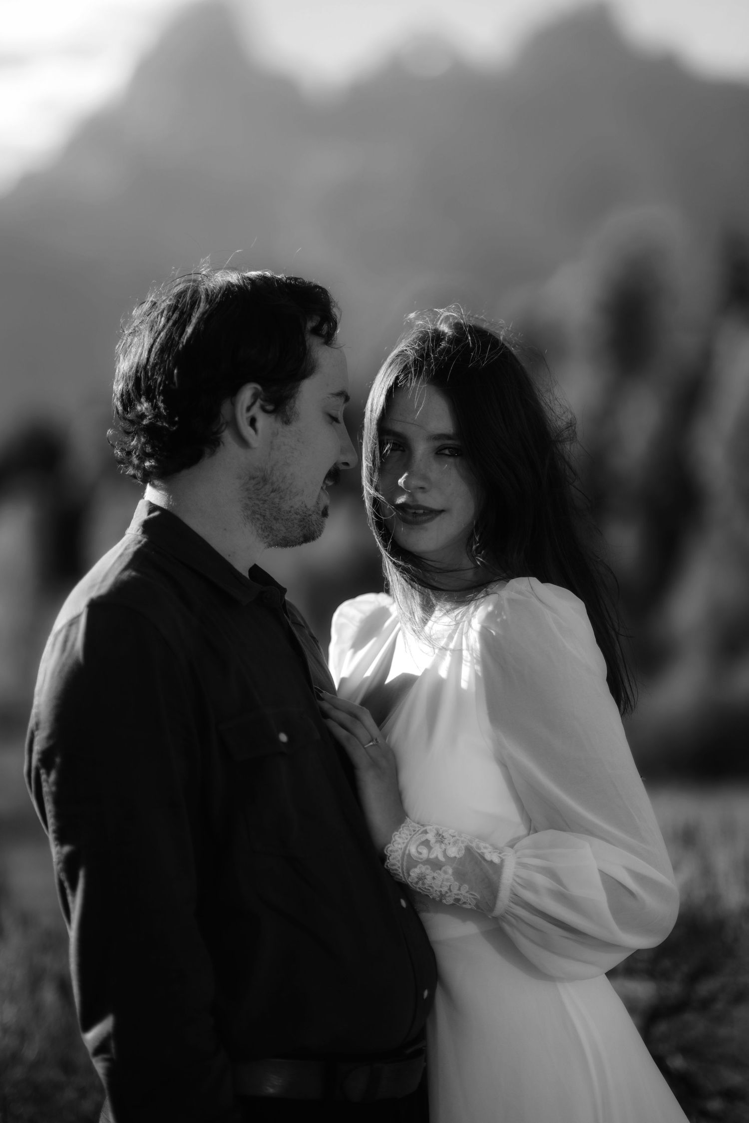 A black and white portrait of a couple in a romantic embrace.