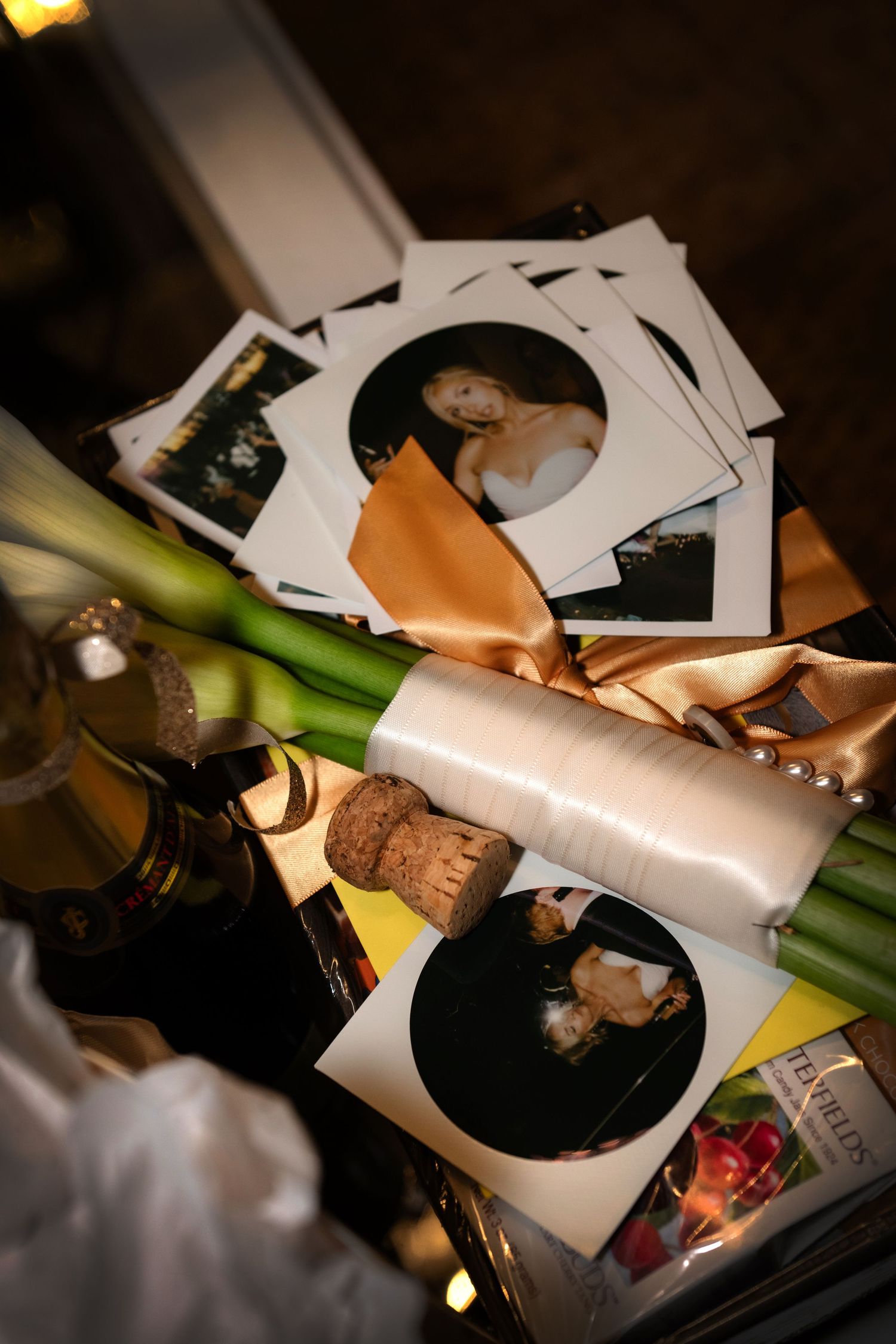 A collection of photographic prints, a bottle of wine, and other objects on a table.