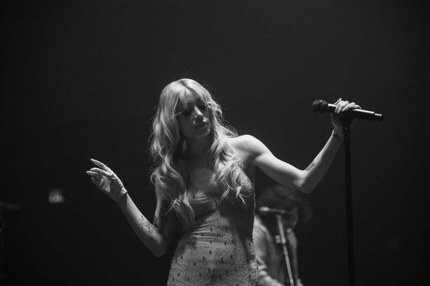 A dramatic black and white performance shot of a singer on stage.