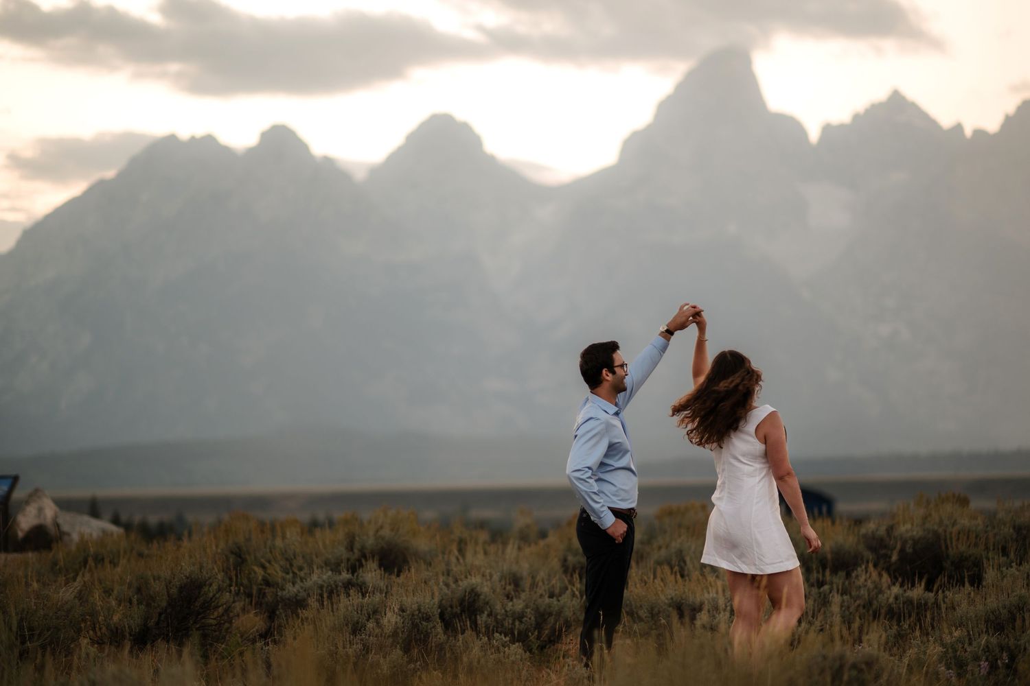 Couple dancing in a field with the Grand Teton mountain range at sunset in Wyoming.