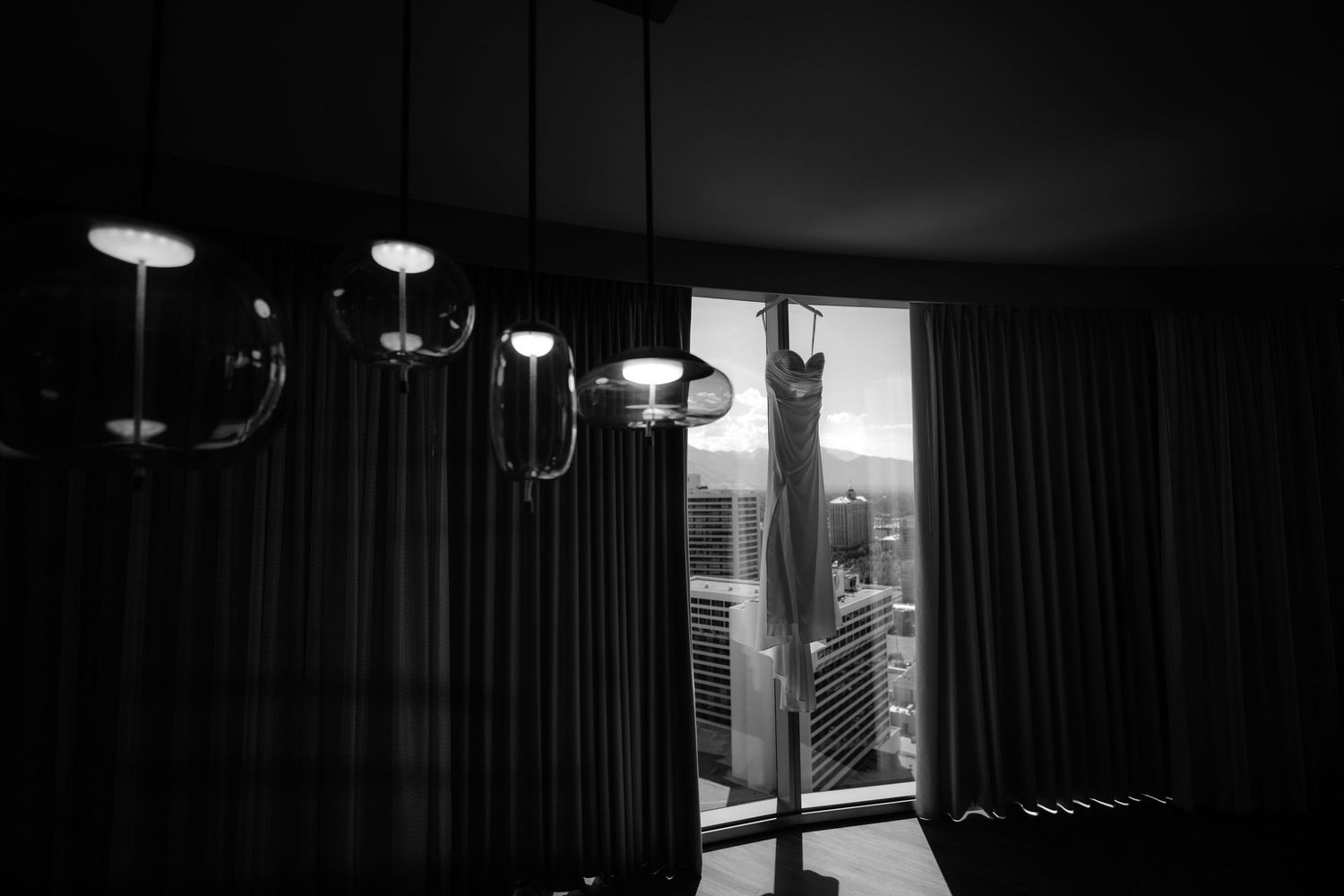 A black and white image shows a room with hanging light fixtures and a window.