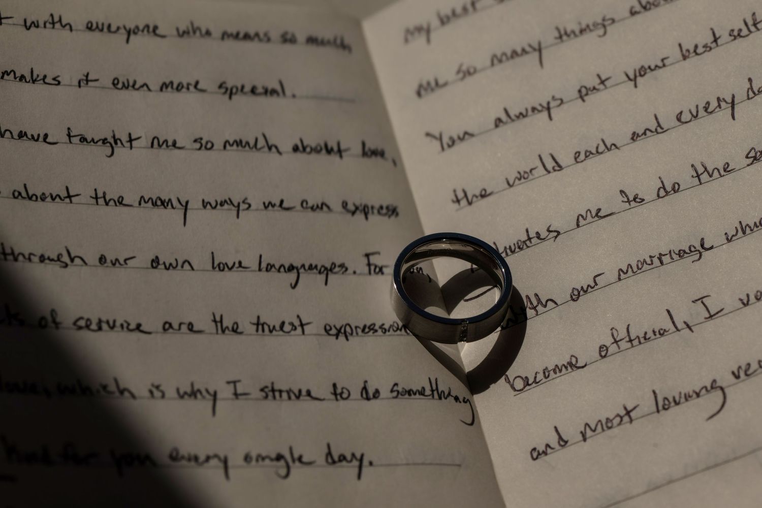 Two wedding rings resting on handwritten wedding vows letter, romantic marriage proposal note with cursive writing.