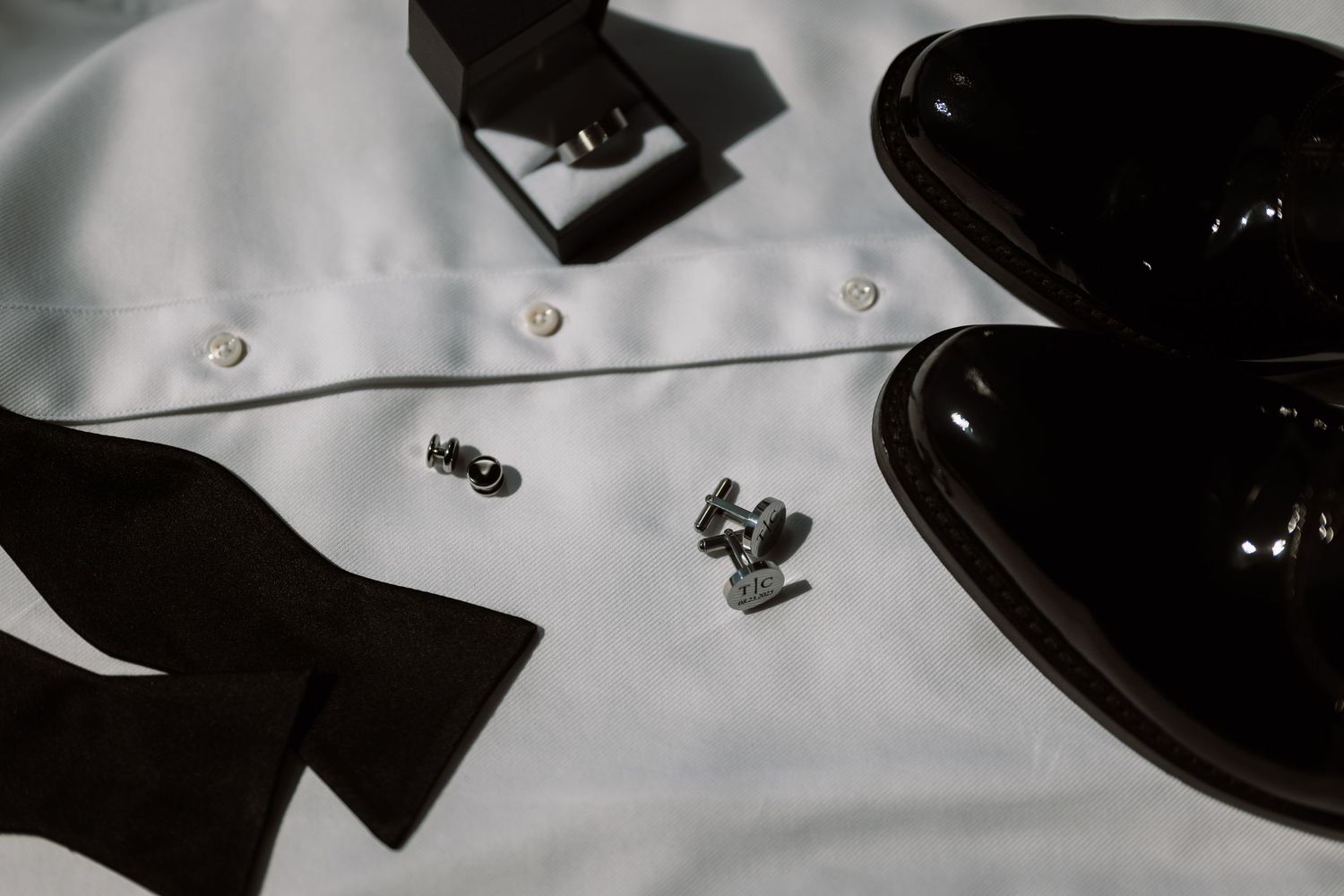 A close-up black and white image of various jewelry items, including a ring, on a surface.