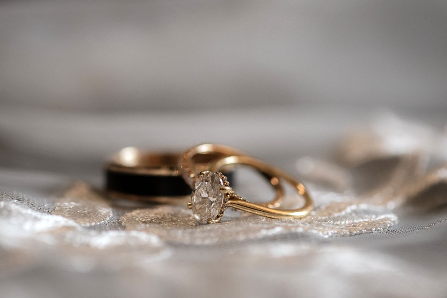 A close-up of a gold ring with a diamond on a white cloth.