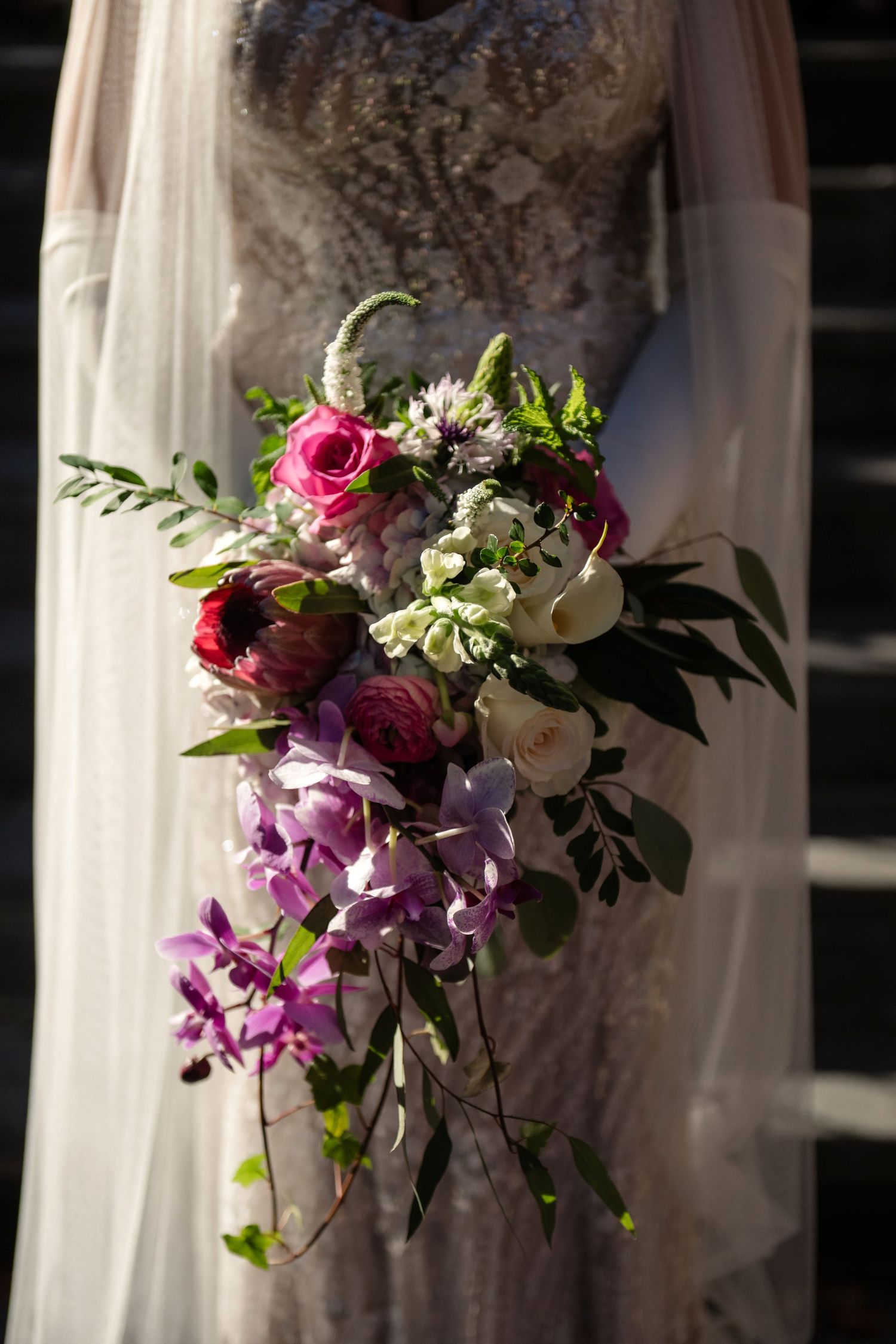 A close-up image shows a bouquet of vibrant flowers including roses and orchids held by a person.