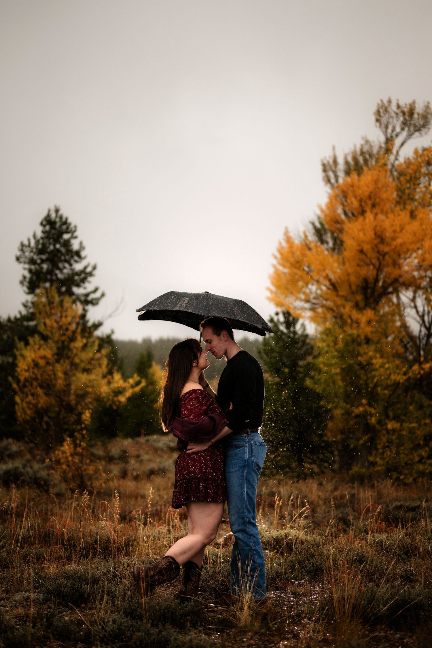 A couple embracing in a scenic mountain landscape with autumn foliage.