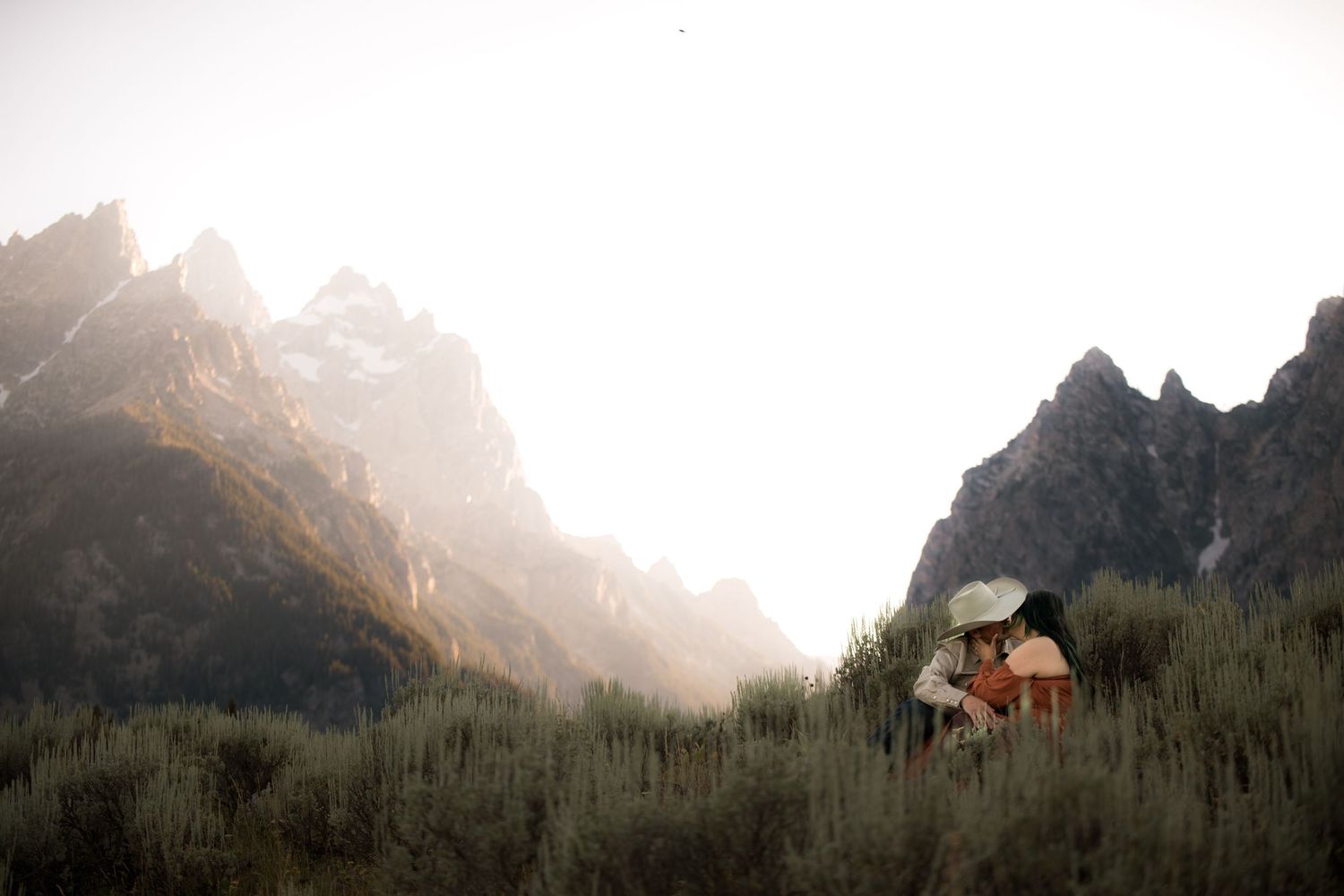 A couple dancing in a mountainous landscape at sunset.