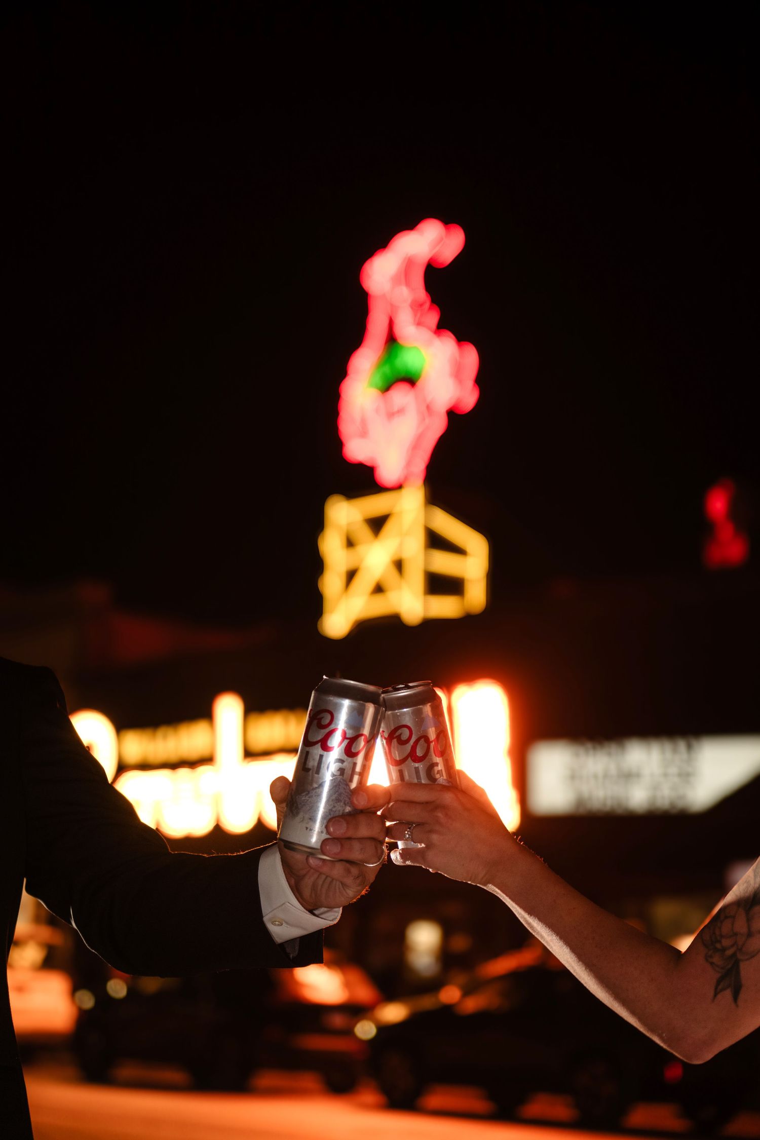 A person holds a glass of wine in front of a neon sign.