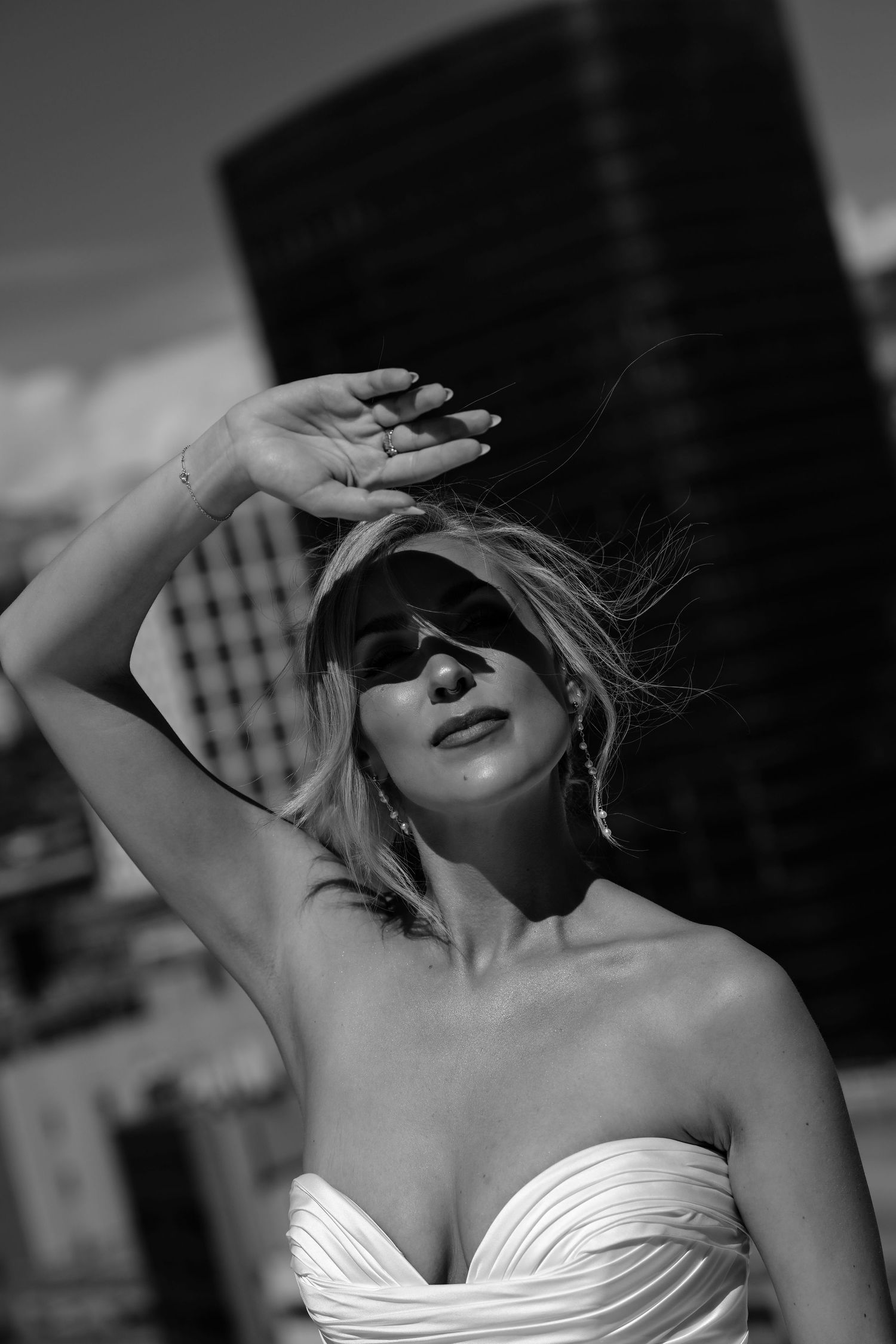 A woman in a white dress posing with her arms raised.