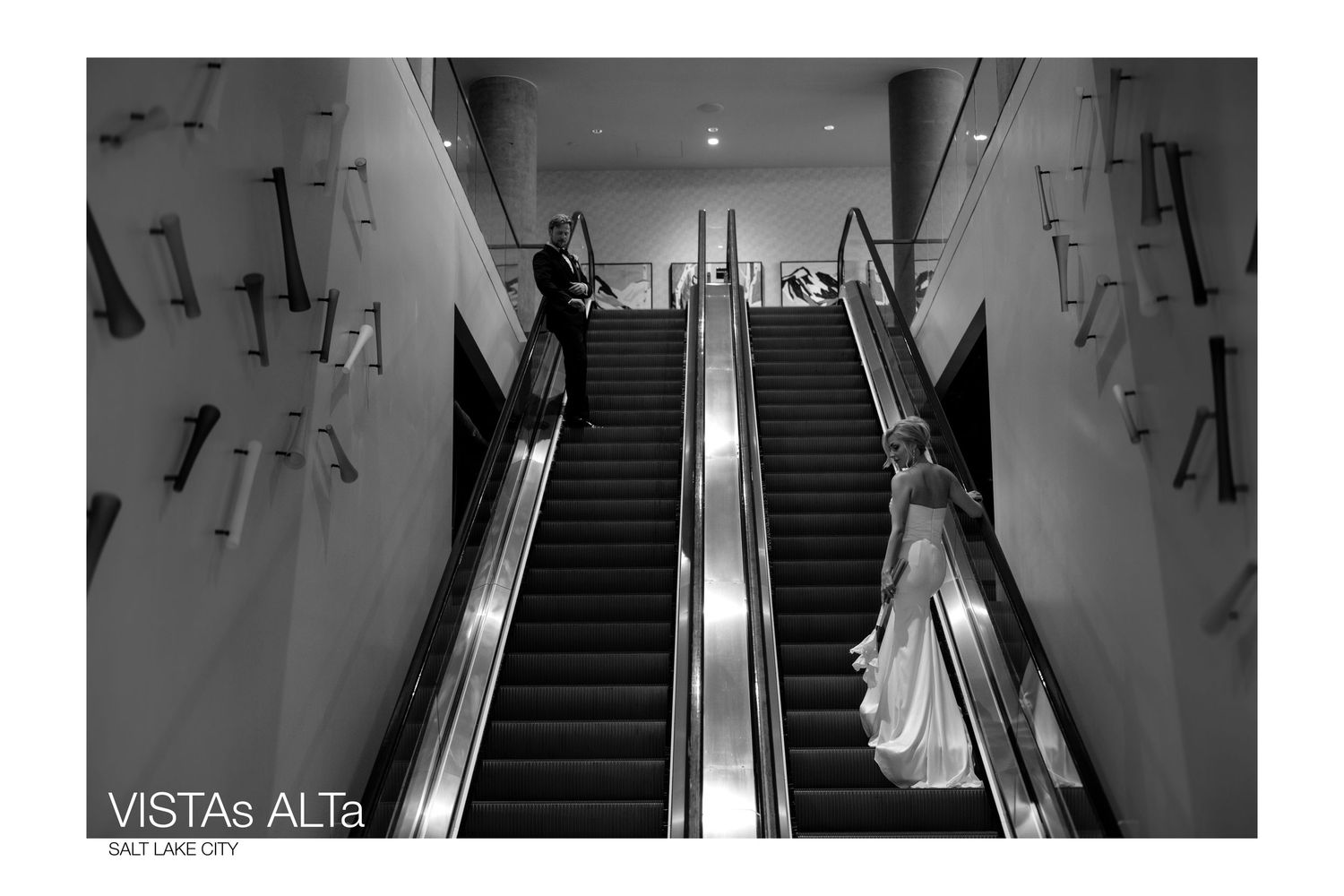 Bride and groom on escalators in black and white wedding photo at Vistas Alta Salt Lake City venue.