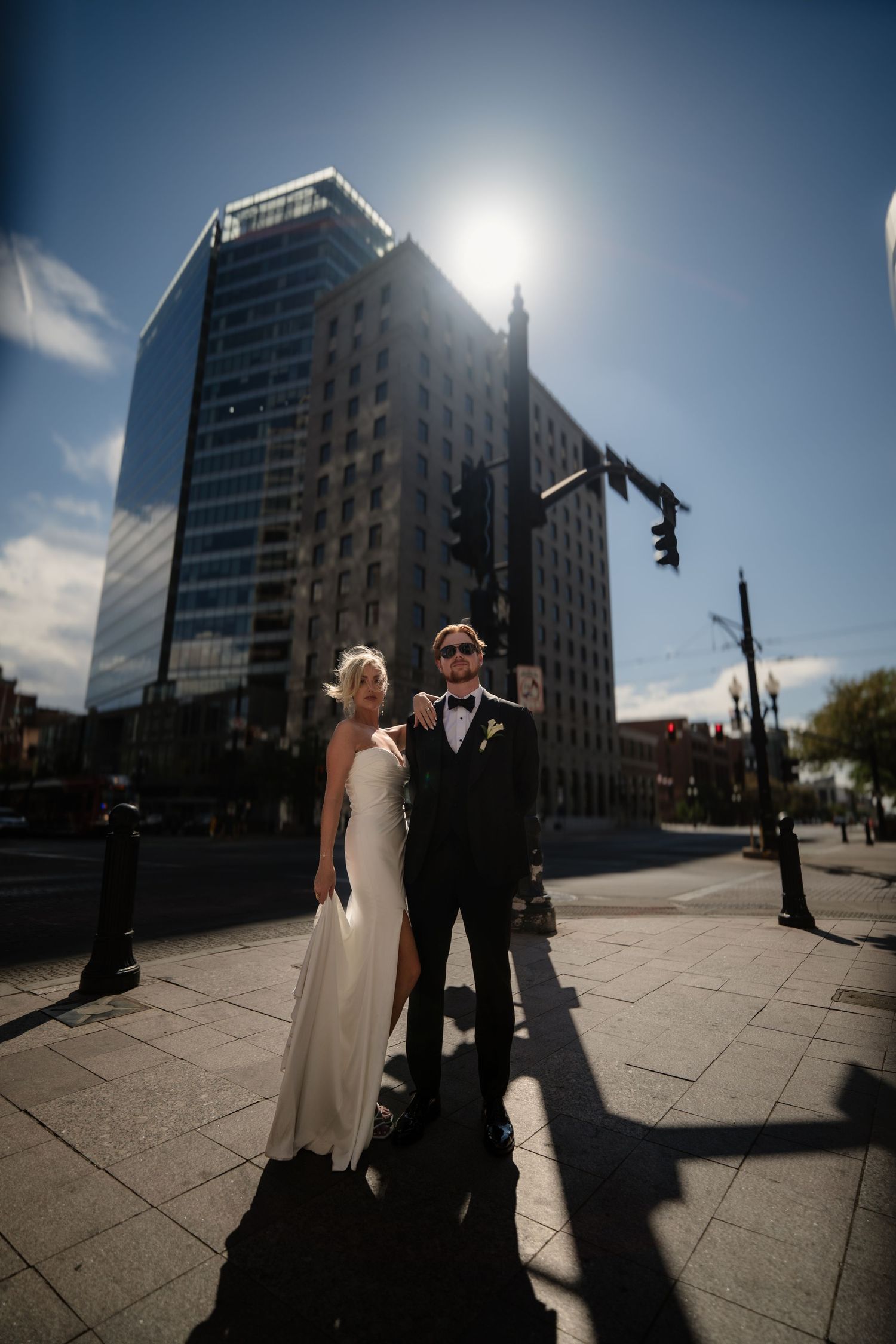 A bride and groom posing together in a city setting.