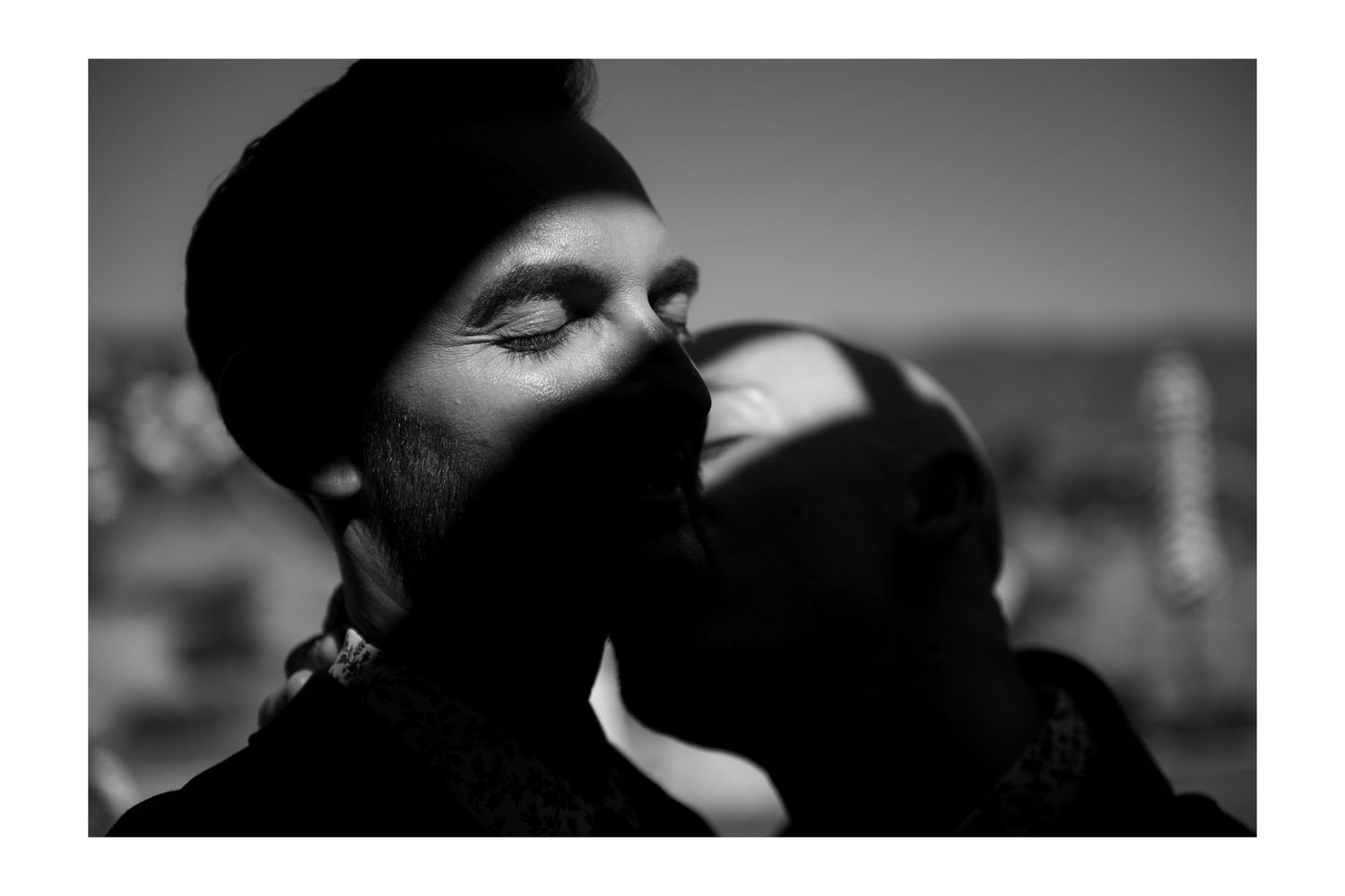 Black and white photo of a bearded man with closed eyes being kissed on the cheek outdoors. LGBTQ Weddings in Salt Lake City