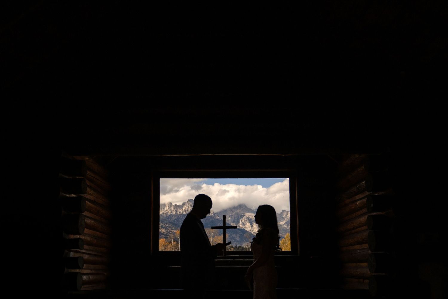 A silhouette of a couple standing in front of a window, with the city skyline visible in the background.