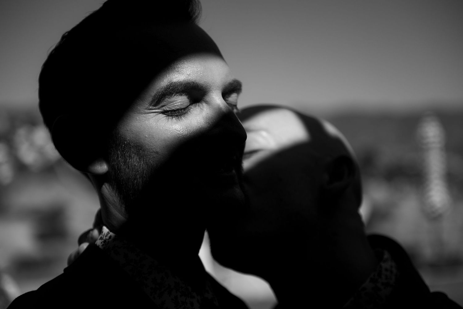 Intimate black and white portrait of couple with closed eyes in soft dramatic light.