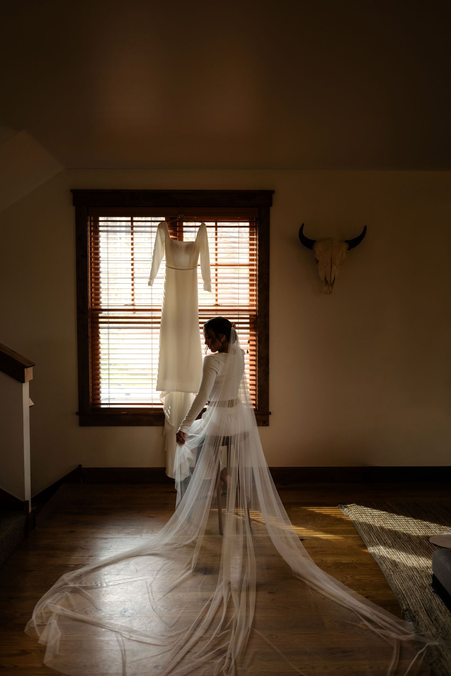 A bride's dress hangs in a window with a scenic view.