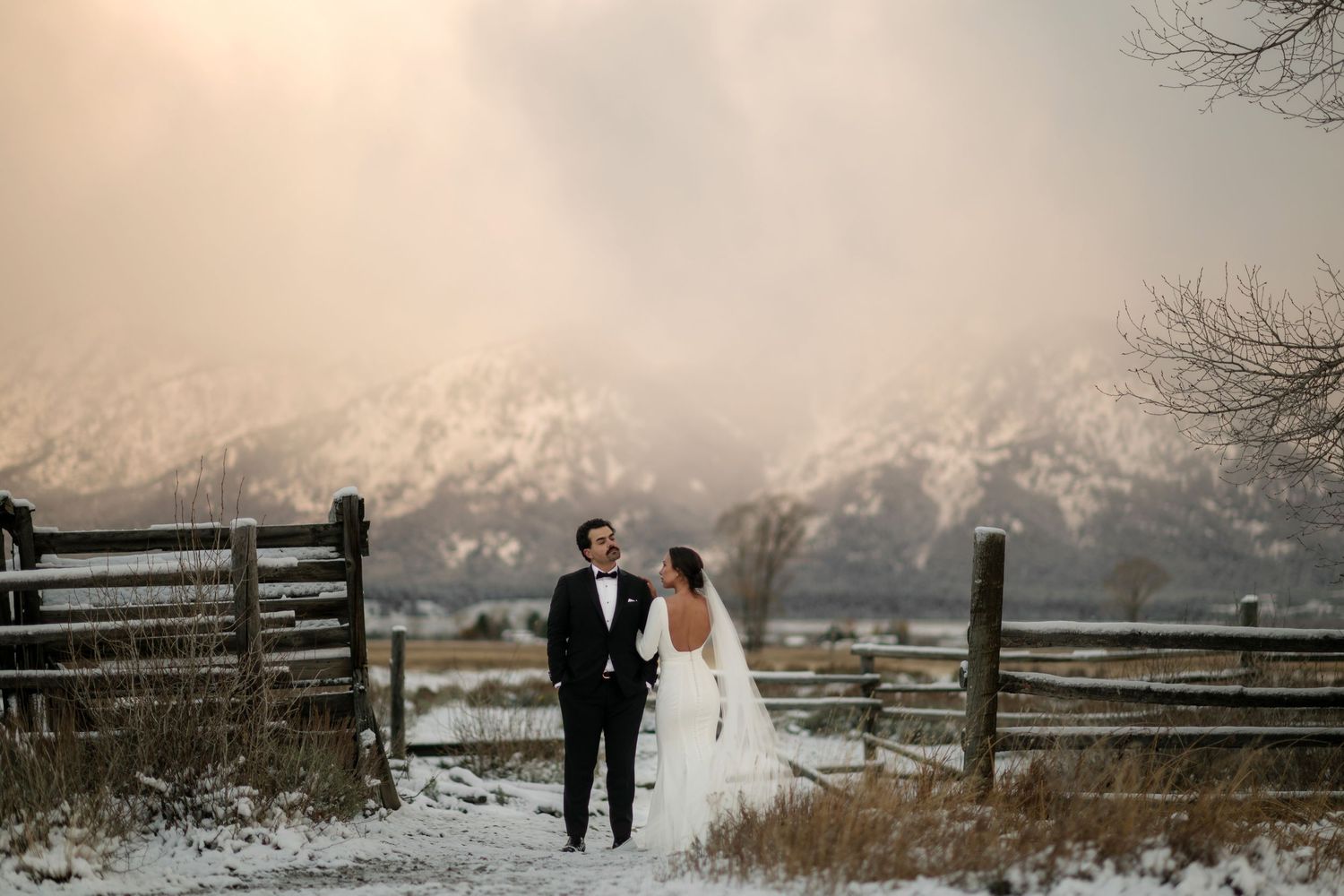A bride and groom standing together in a snowy outdoor setting.
