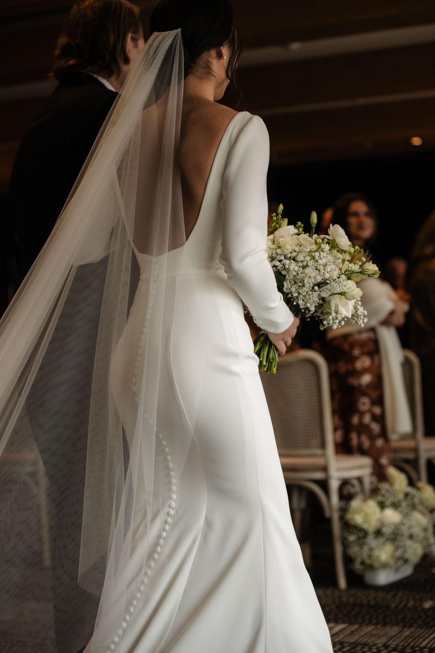 A bride walking down the aisle in a long white wedding dress with a veil.