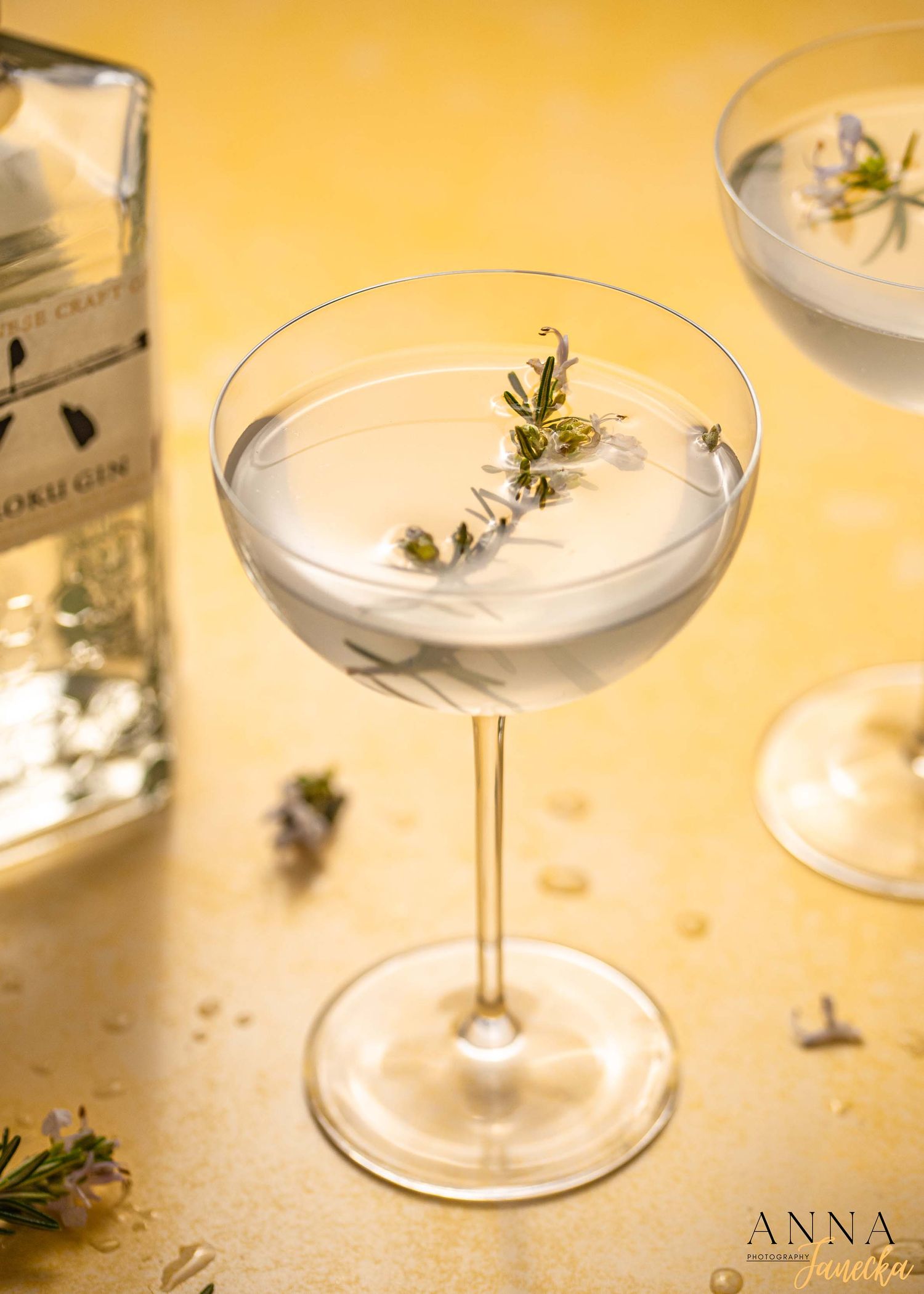 Classic martini garnished with fresh herbs in a coupe glass on yellow background.