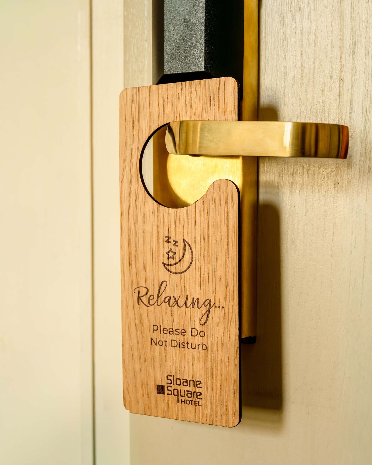 Wooden do not disturb door hanger on gold handle at Sloane Square Hotel, engraved with Relaxing Please Do Not Disturb.