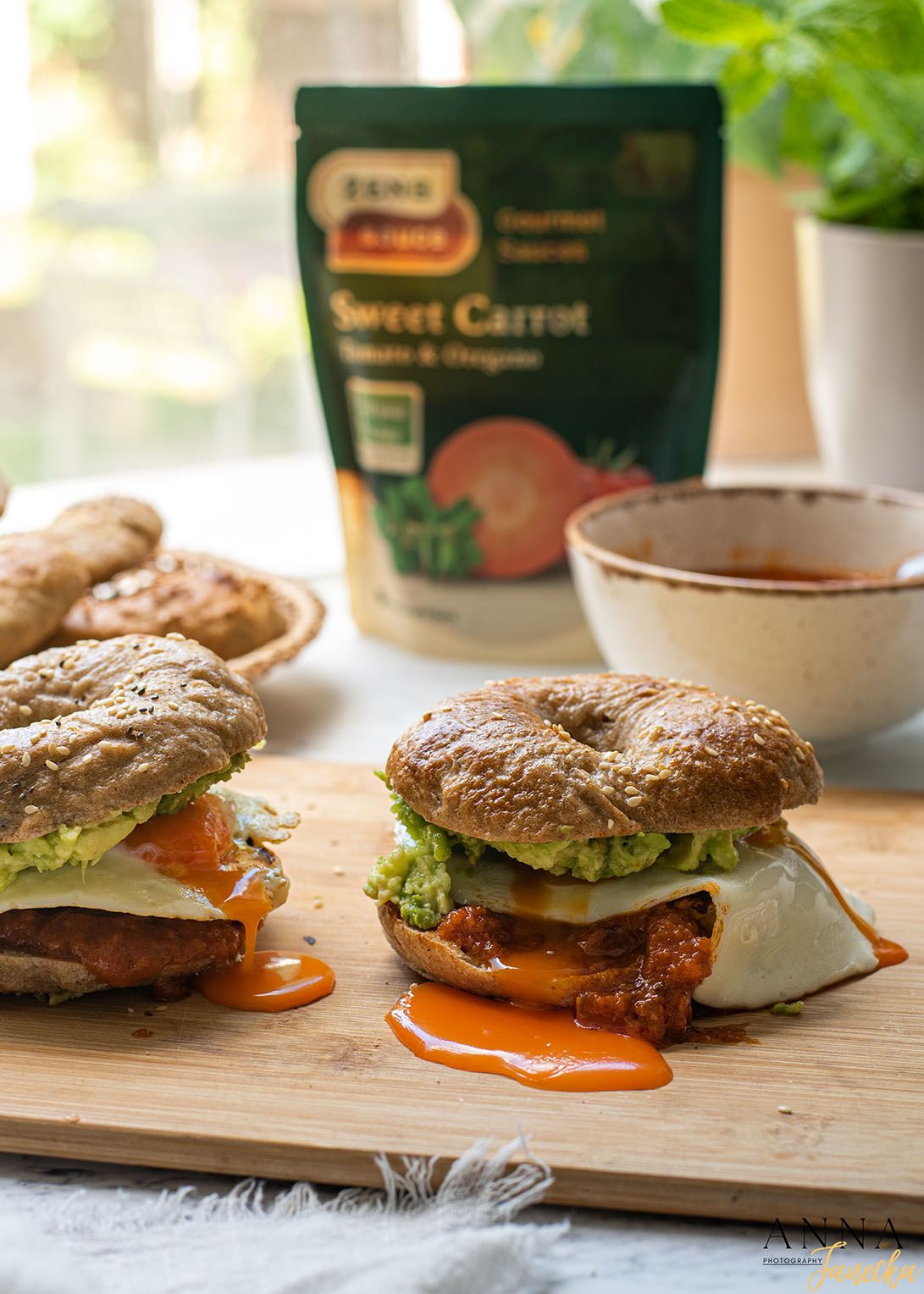 Two gourmet burgers with melted cheese and sauce on a wooden cutting board.
