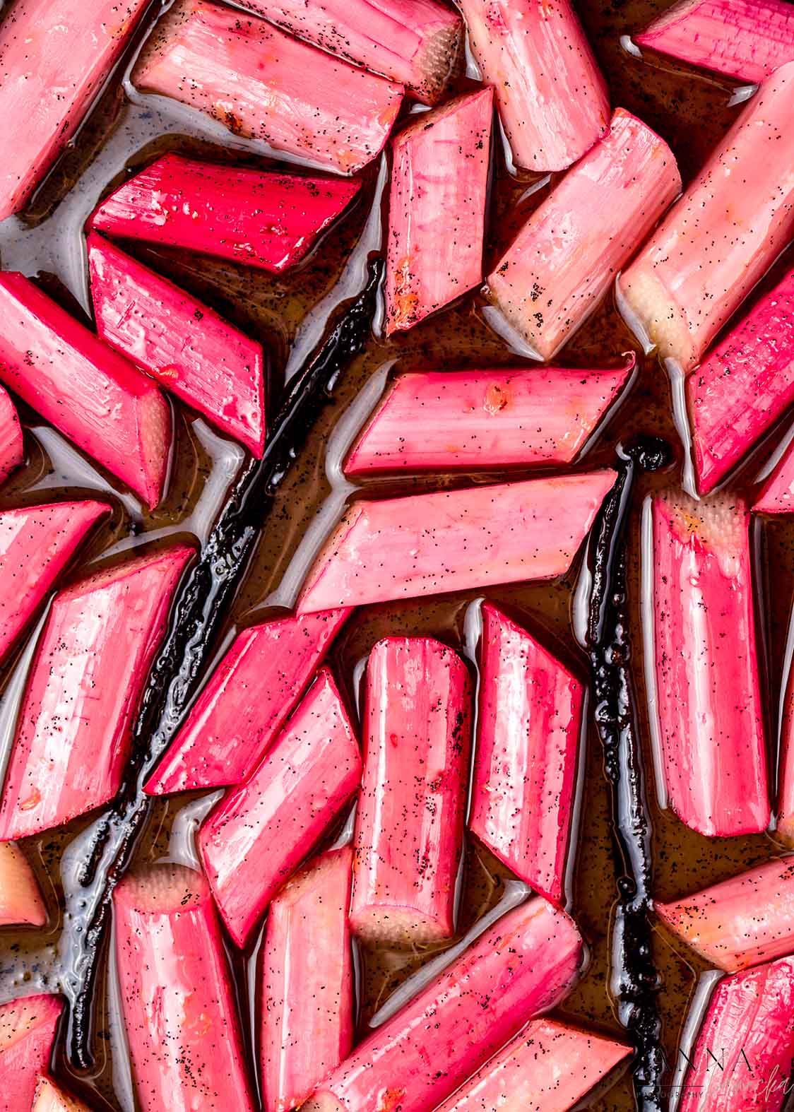 Roasted pink rhubarb pieces in dark syrup arranged in a pattern.
