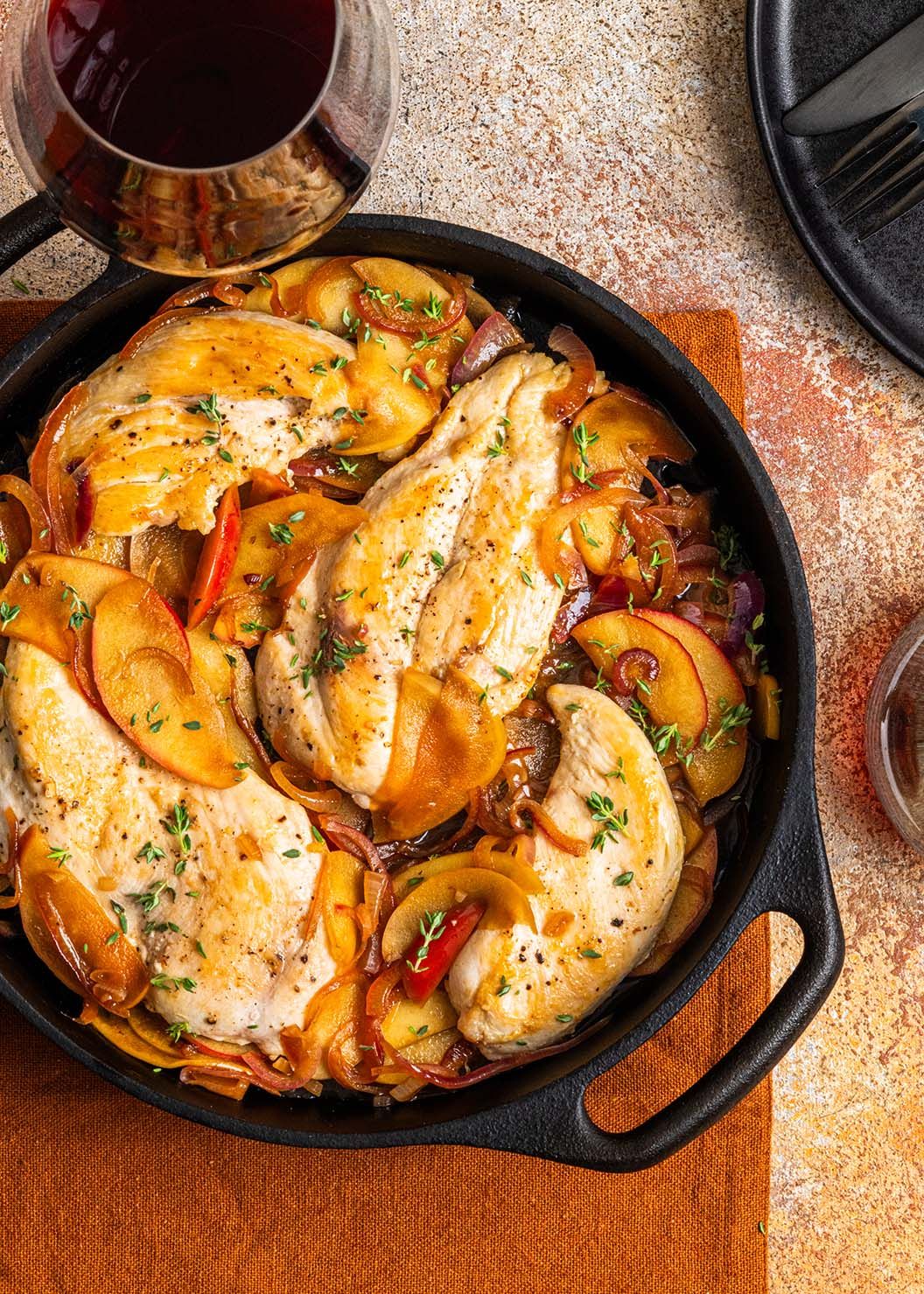 Juicy chicken breast with herbs and vegetables served in a cast iron skillet with white wine sauce.