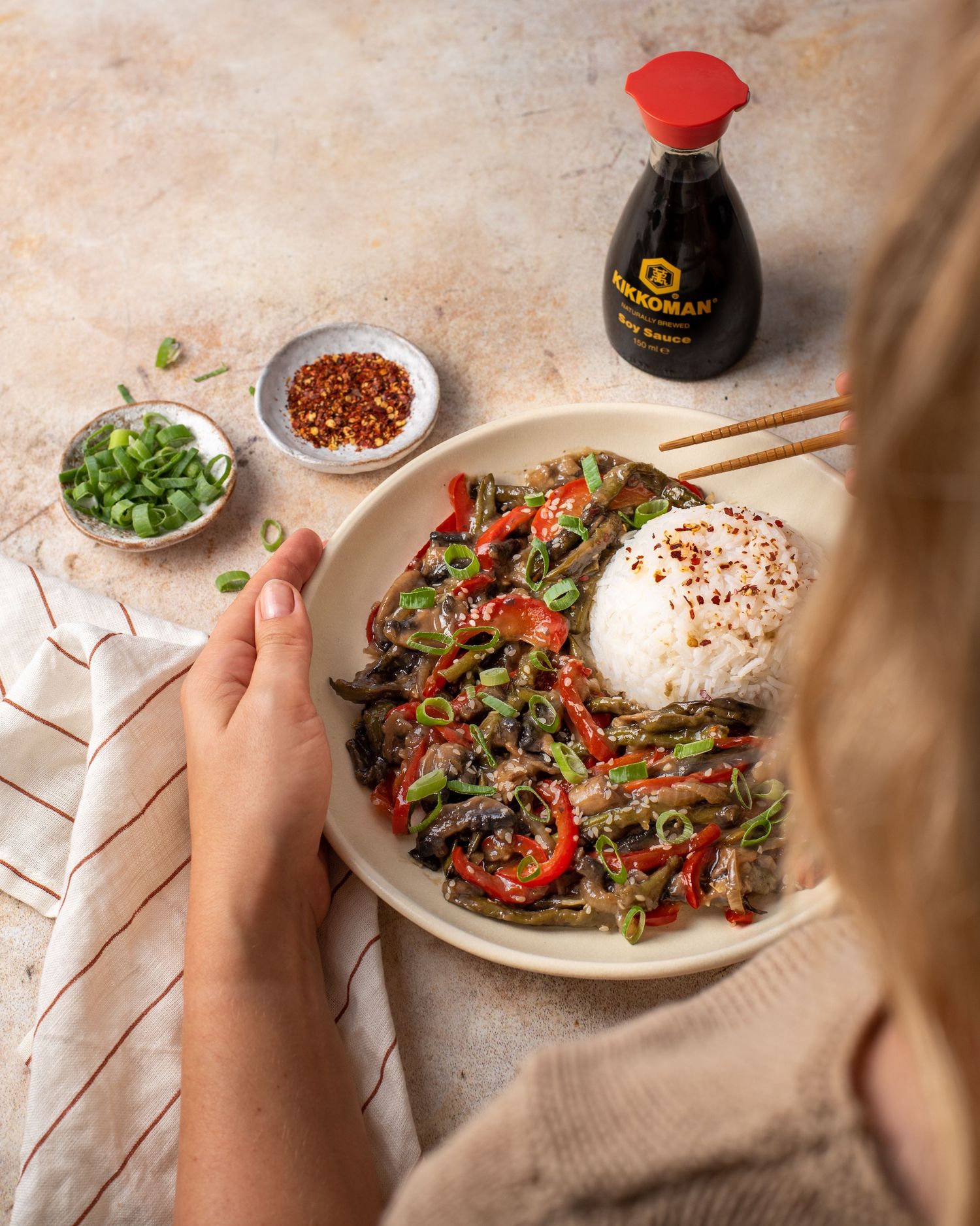 Step by step preparation of beef stir fry with rice and vegetables on a textured surface.