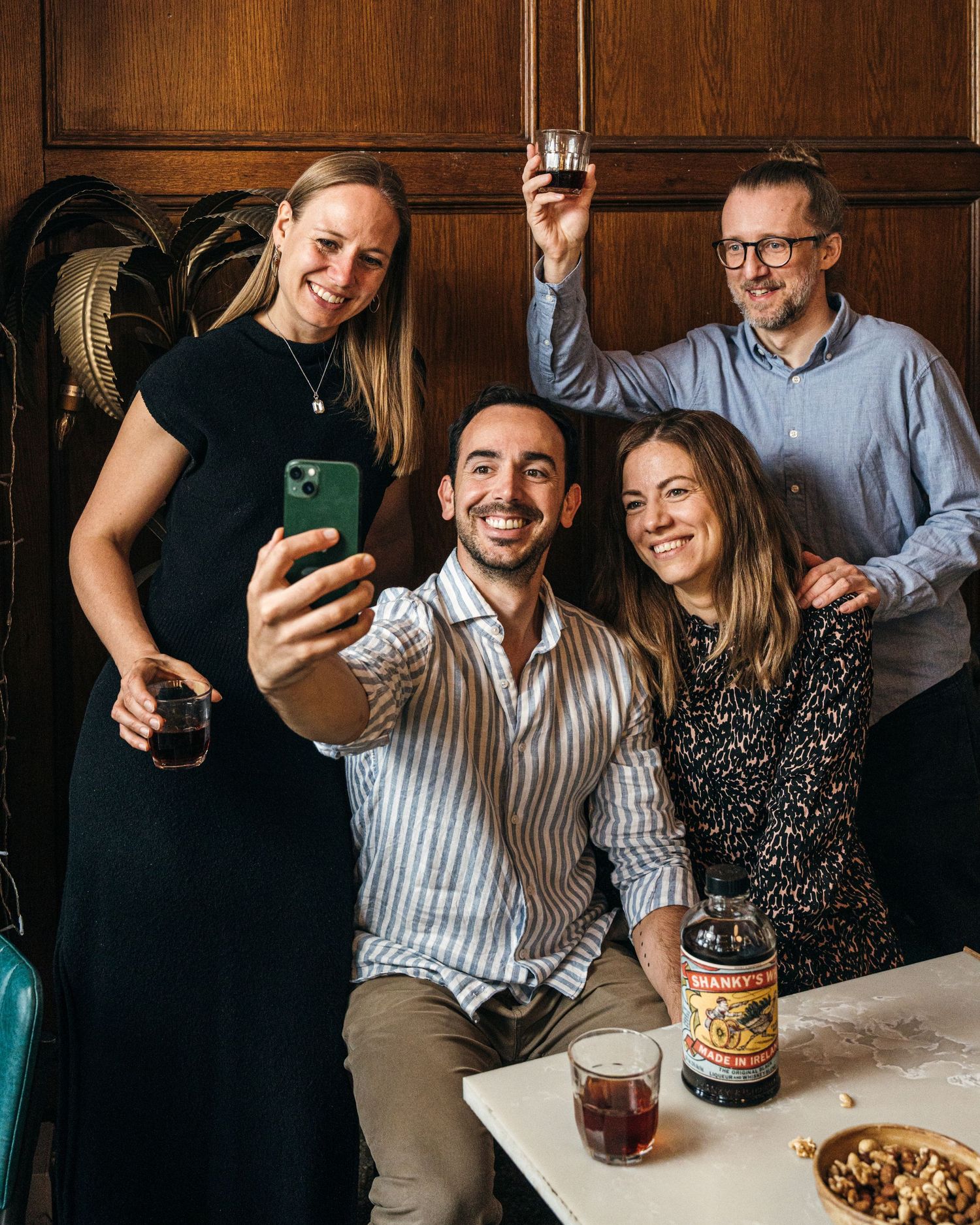 A group enjoying drinks and appetizers at a rustic wooden table in a cozy restaurant setting.