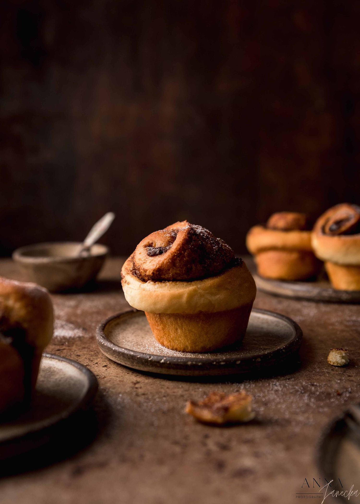 Freshly baked cinnamon rolls on rustic plates photographed in a sequence.