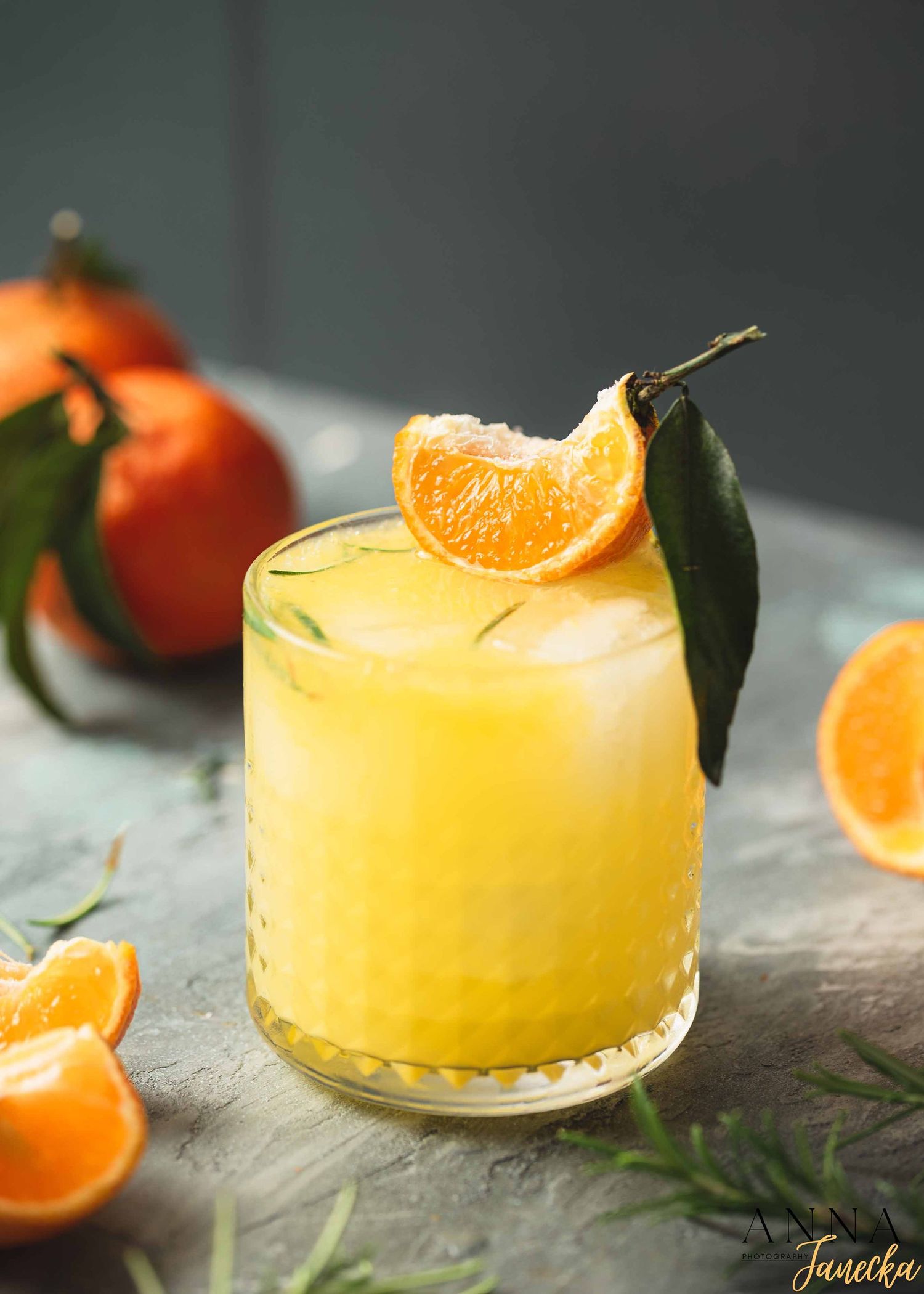 Fresh orange juice cocktail garnished with citrus slice and leaf.