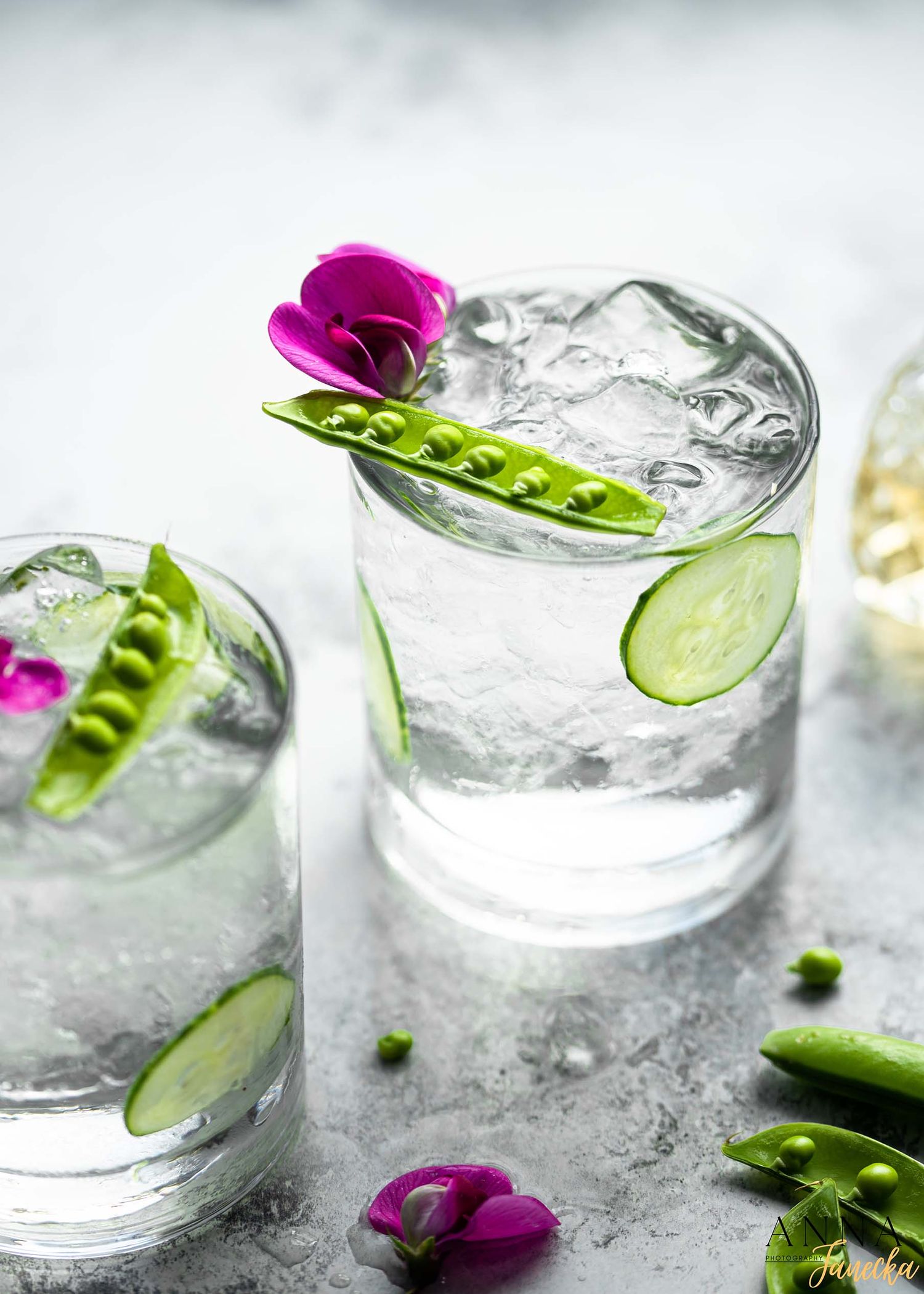 Refreshing gin and tonic with cucumber slices and purple flower garnish.