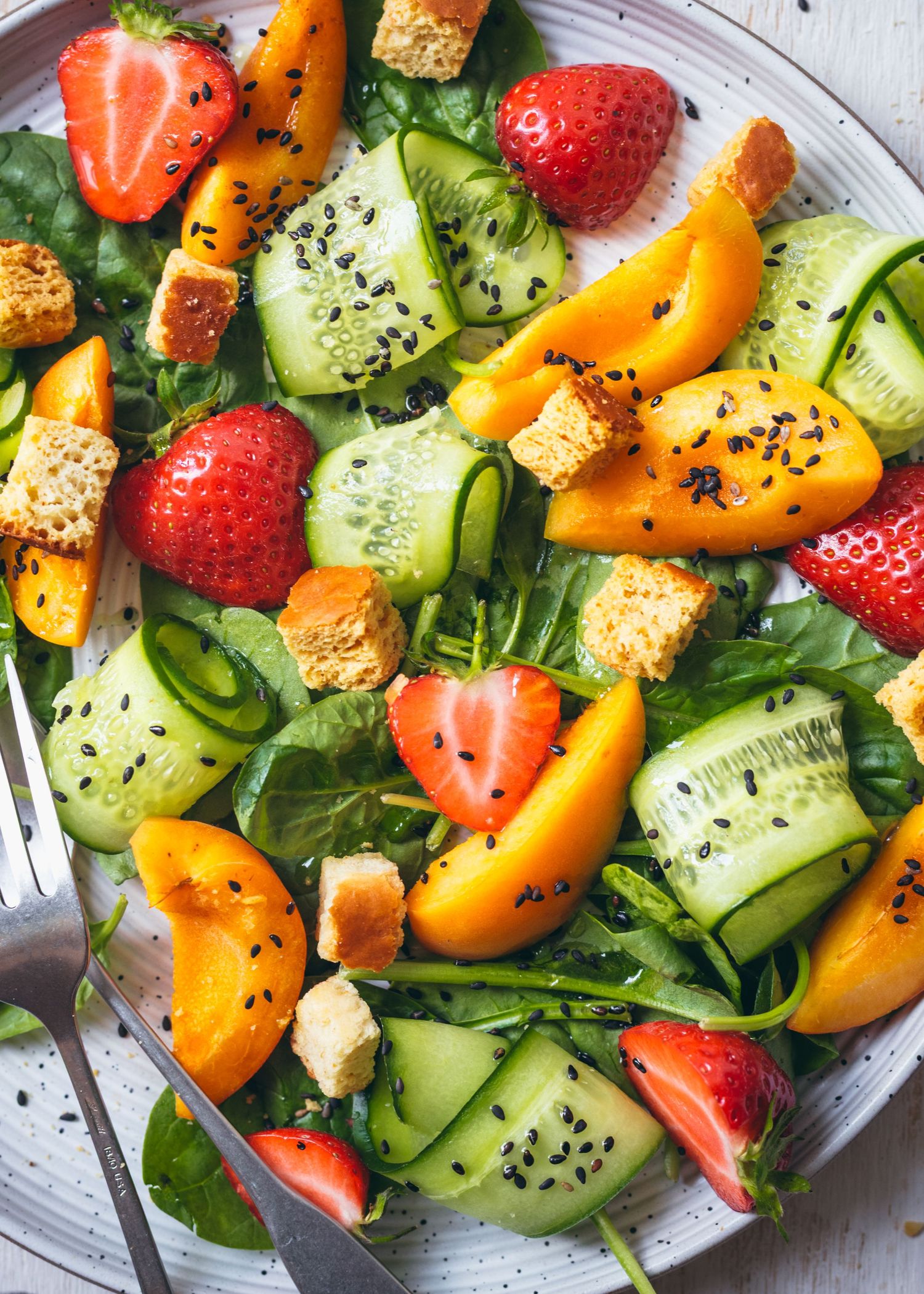 Fresh summer salad with strawberries, cucumbers, croutons and yellow peppers.
