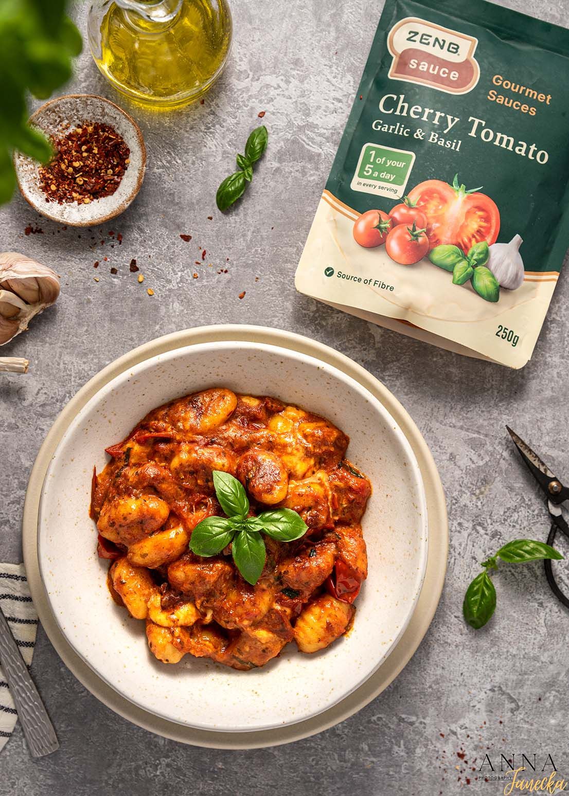 Bowl of gnocchi in cherry tomato sauce garnished with fresh basil leaves and olive oil.