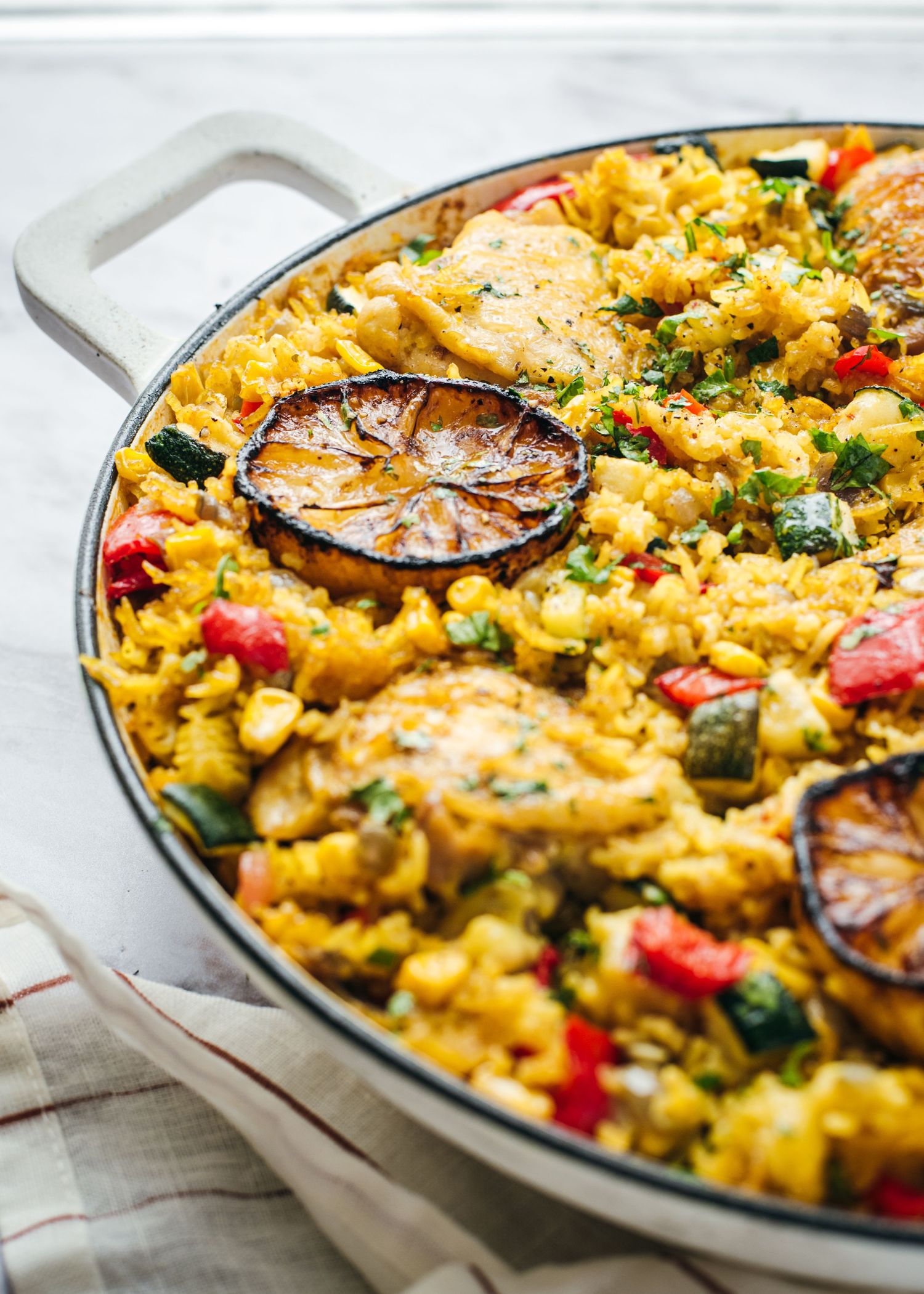 Vibrant Spanish seafood paella with grilled lemons and fresh vegetables in a traditional cast iron pan.