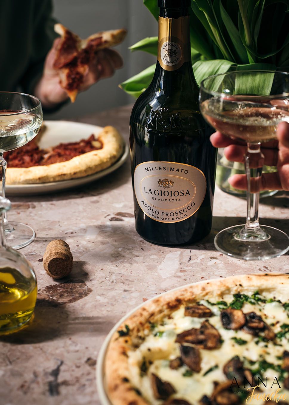 Wine glasses and Italian pizza with a bottle of Lacrima wine on marble table.