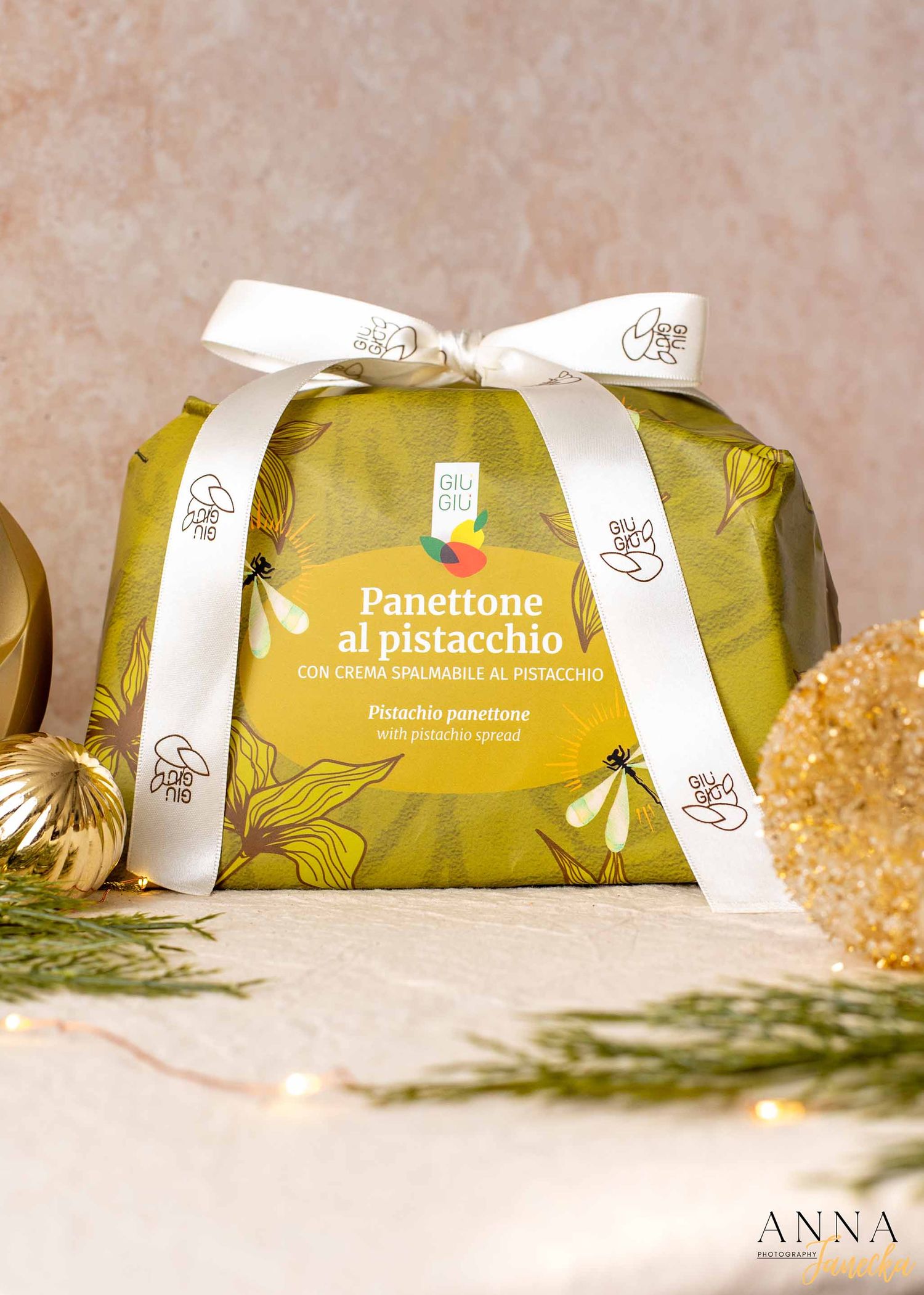 Pistachio panettone in elegant green and gold packaging displayed with holiday decorations.