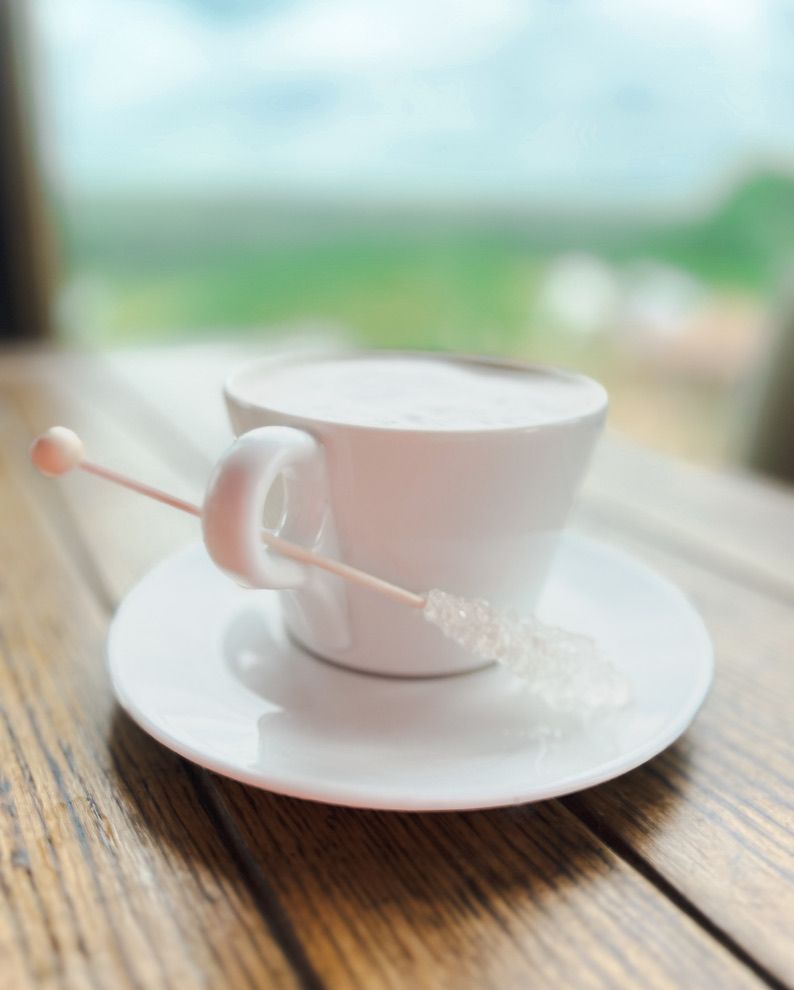 White ceramic coffee cup and saucer on rustic wooden table with shallow depth of field.