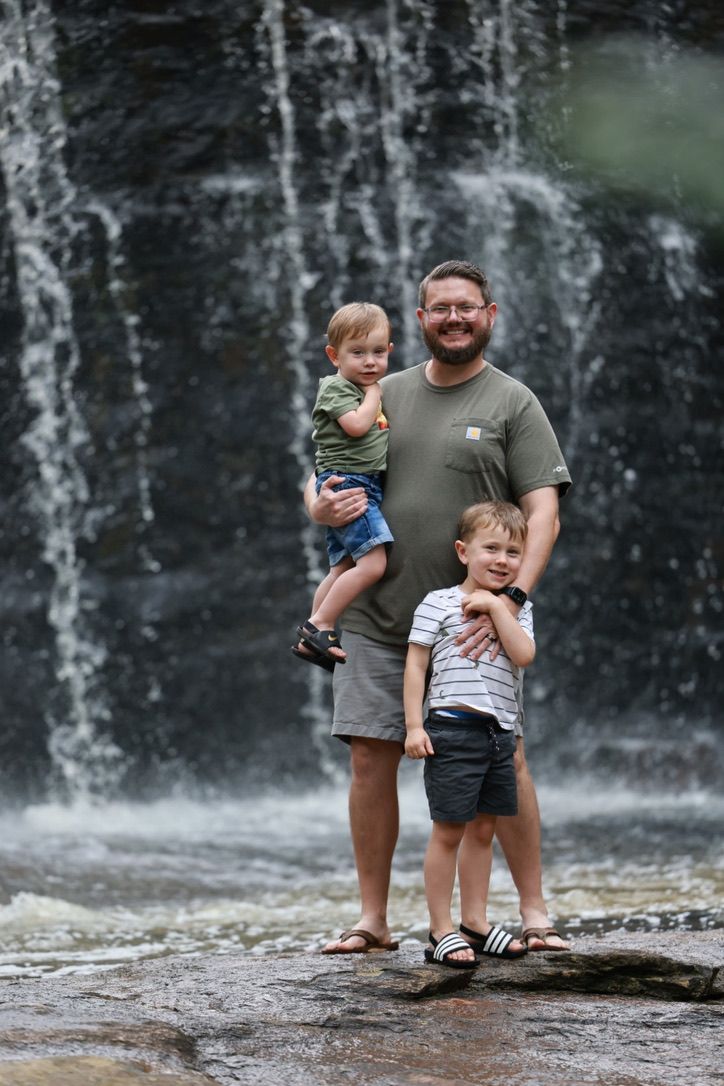 People enjoying a scenic moment in front of a cascading waterfall.