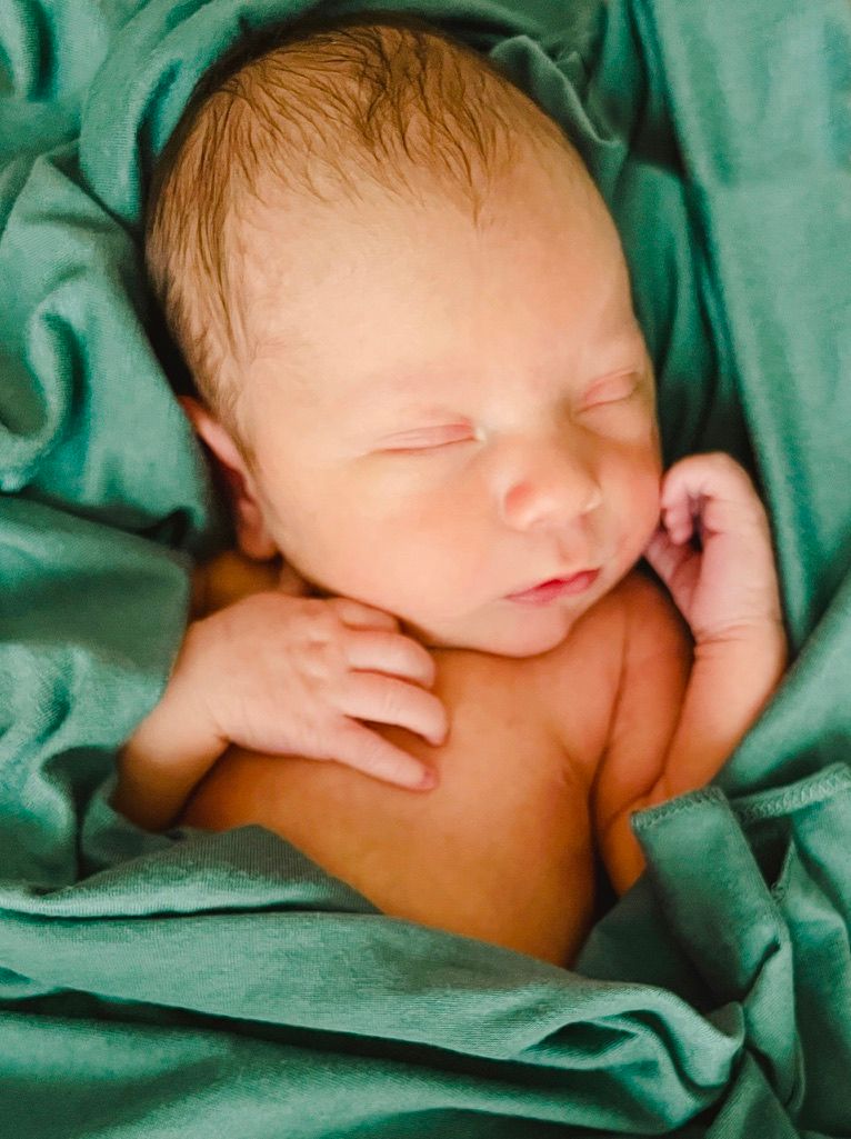 Peaceful sleeping newborn nestled in soft green blankets.