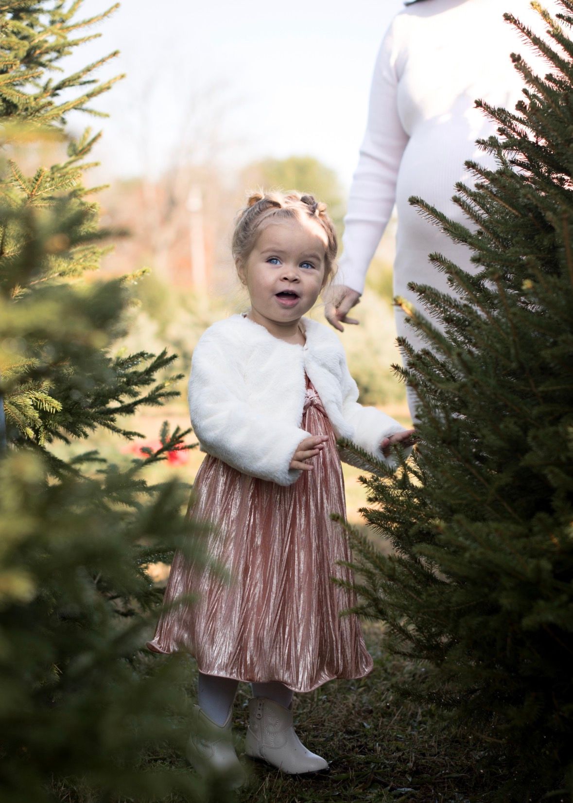 Little girl standing amongst Christmas tree during a holiday mini session in South Jersey, NJ.